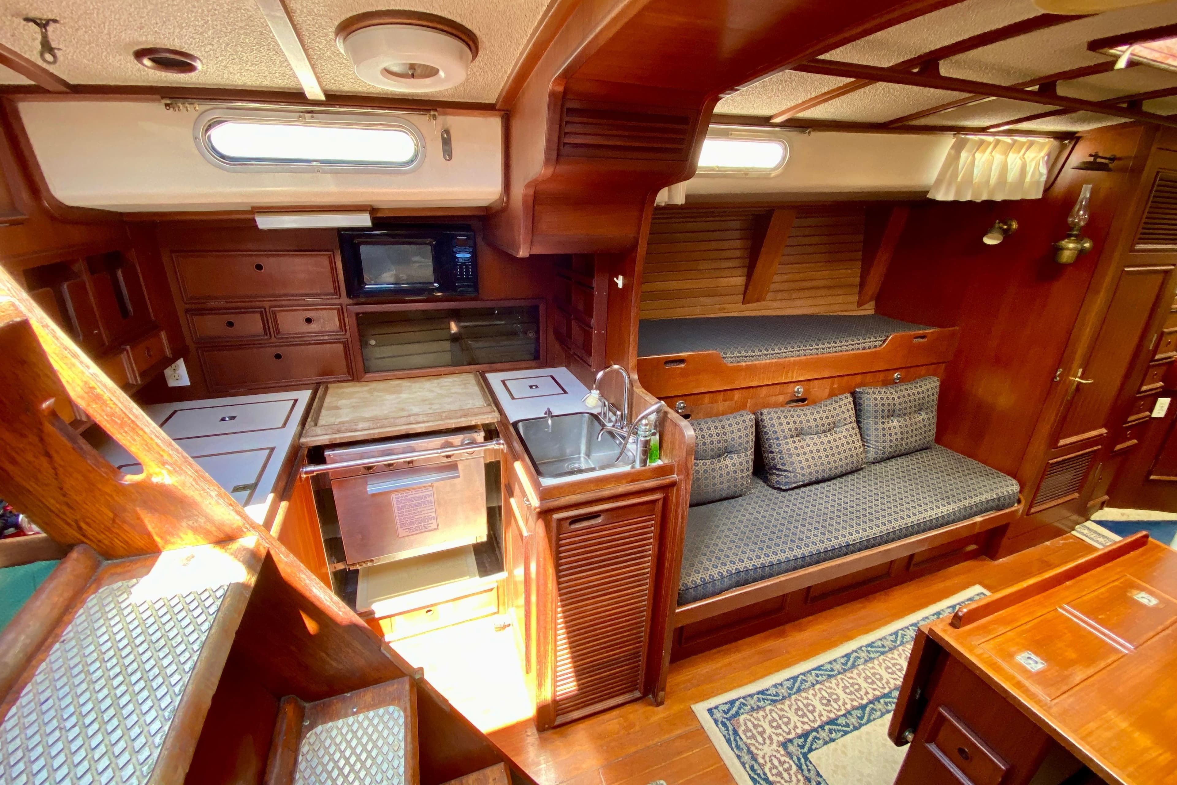 Interior of a 1979 Fuji 40 sailboat with wooden cabinetry and cozy seating area.
