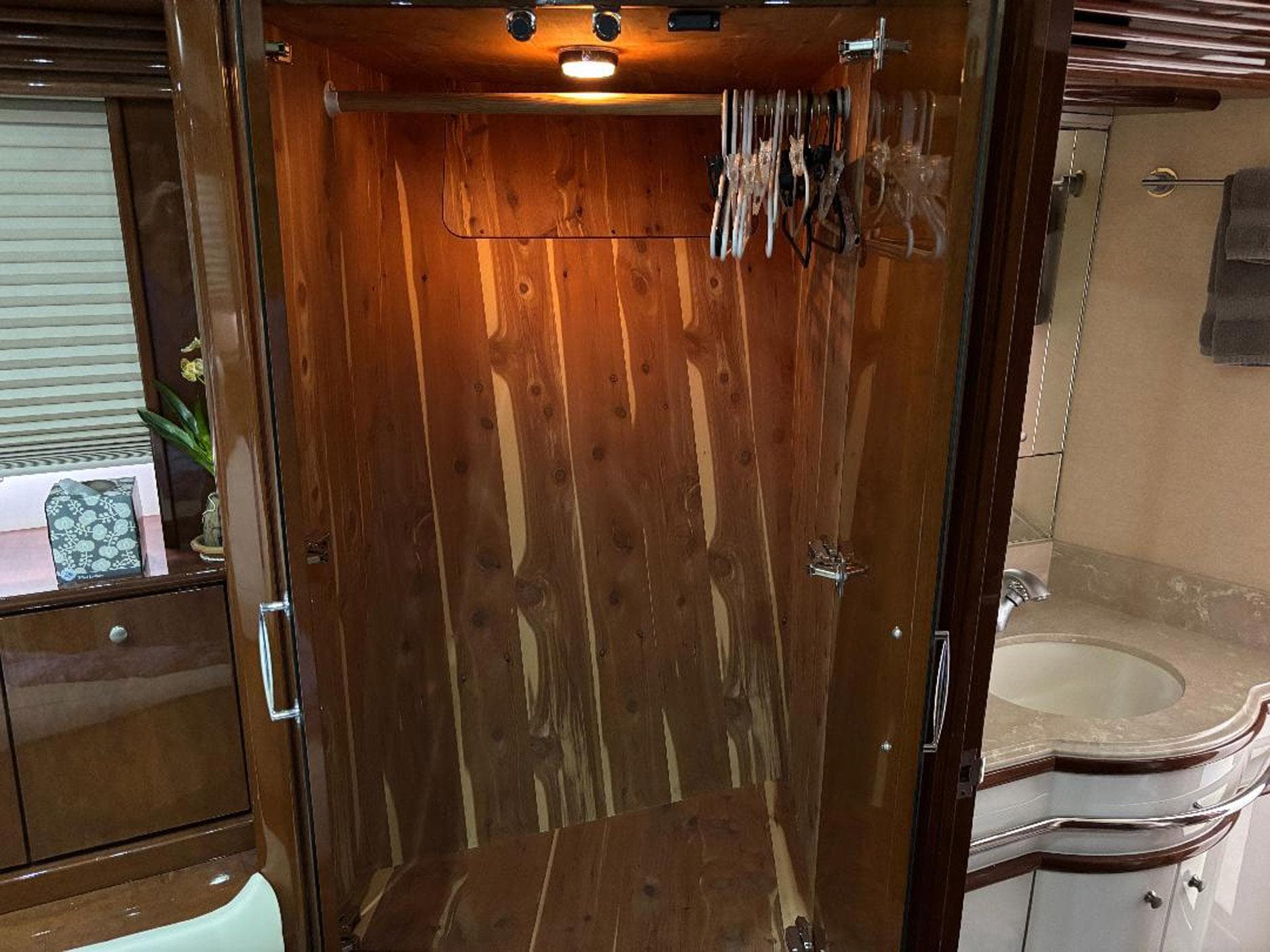Wooden closet interior with hangers in a 2006 Marquis 65 yacht bathroom.