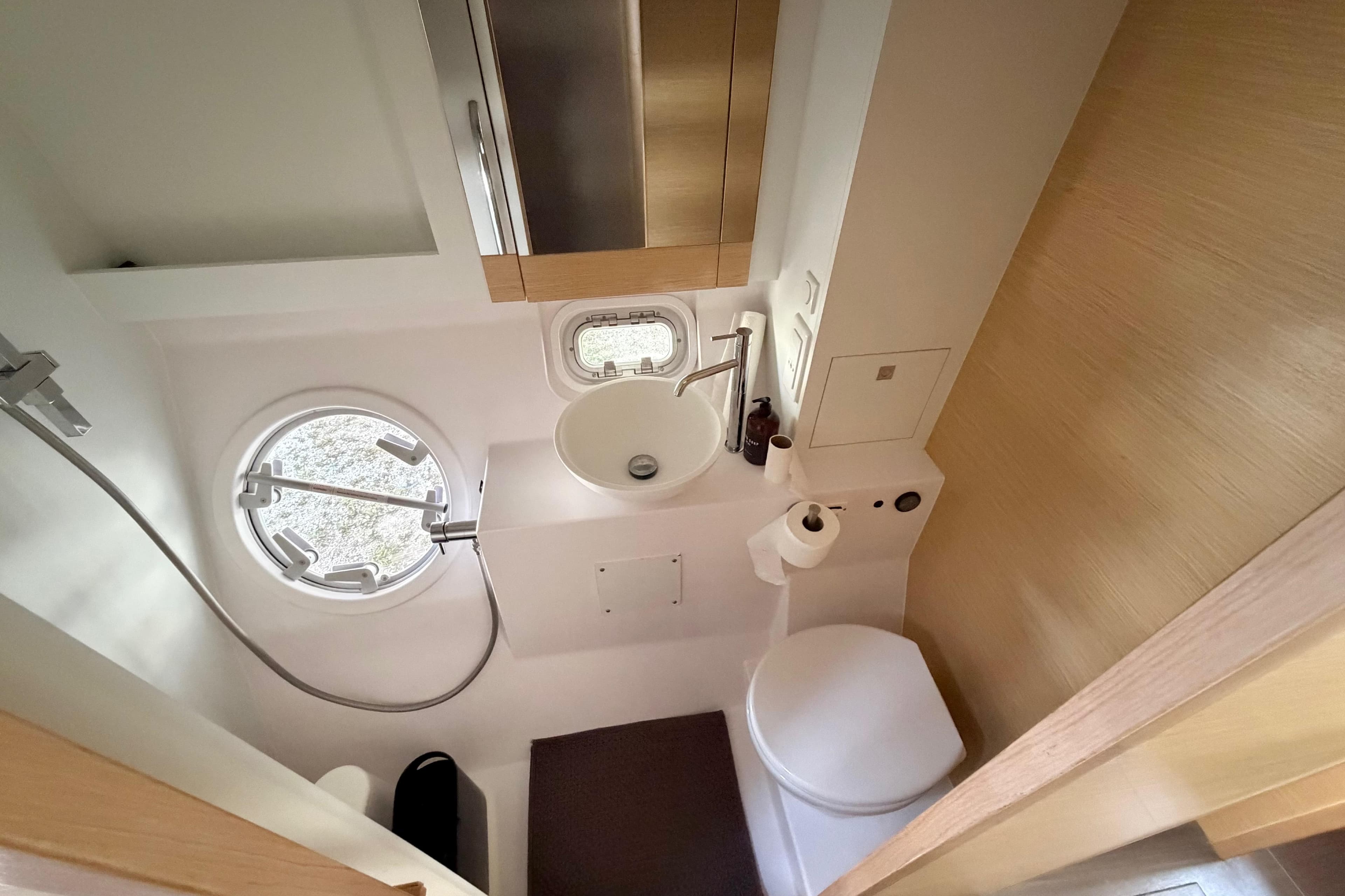 Compact bathroom in a 2016 Outremer 45 yacht with modern fixtures and porthole window.