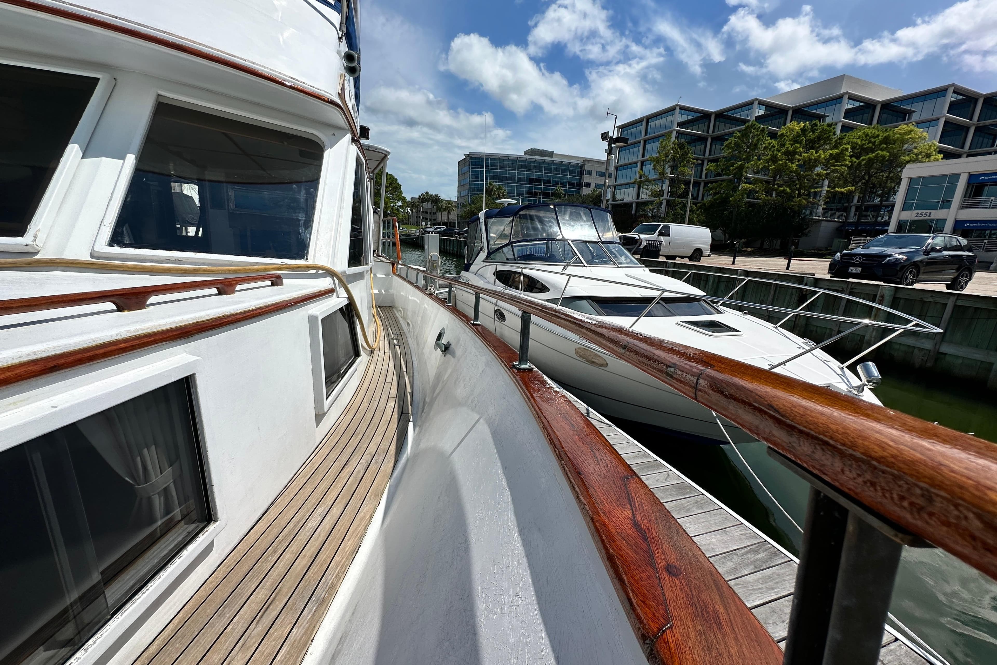 1980 Island Gypsy Flush Aft Deck Trawler-Motor Yacht docked beside modern buildings.