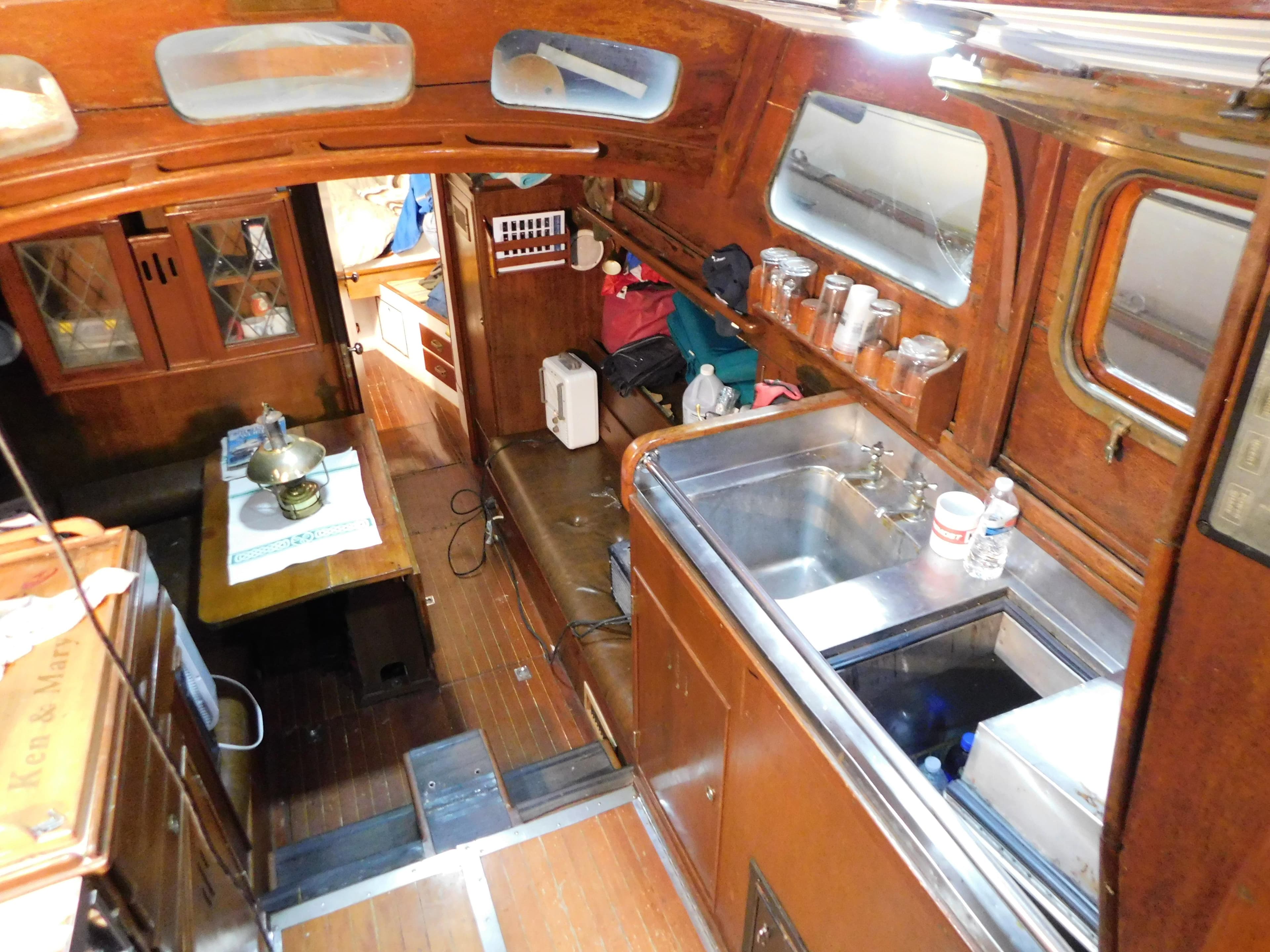 Interior of 1949 Burger Full Keel Steel Auxiliary Ketch with wooden cabinetry and compact kitchen.