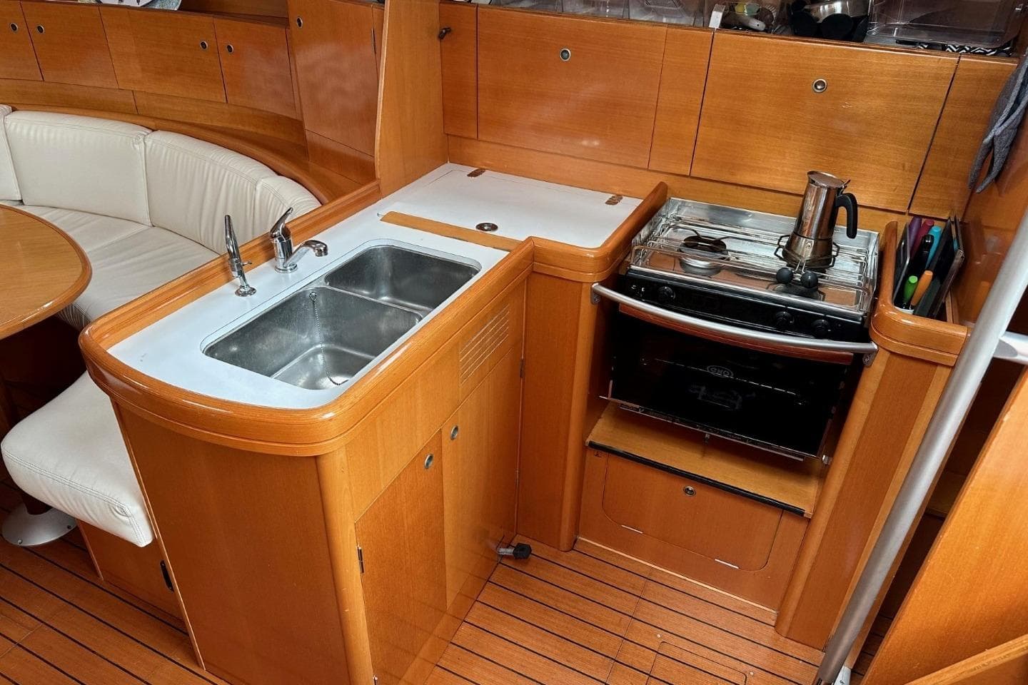 Interior of 2007 Beneteau First 44.7 yacht with wooden cabinetry and compact kitchen area.