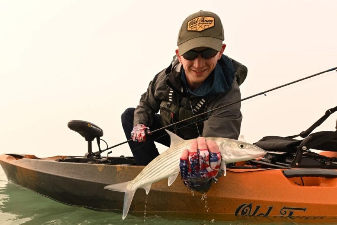 Man fishing from 2023 Old Town Sportsman Autopilot 120 kayak, holding a fish.