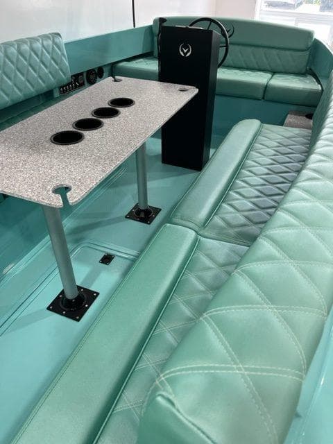 2023 Vision Marine Technologies Fantail 217 interior with teal seating and a table with cup holders.