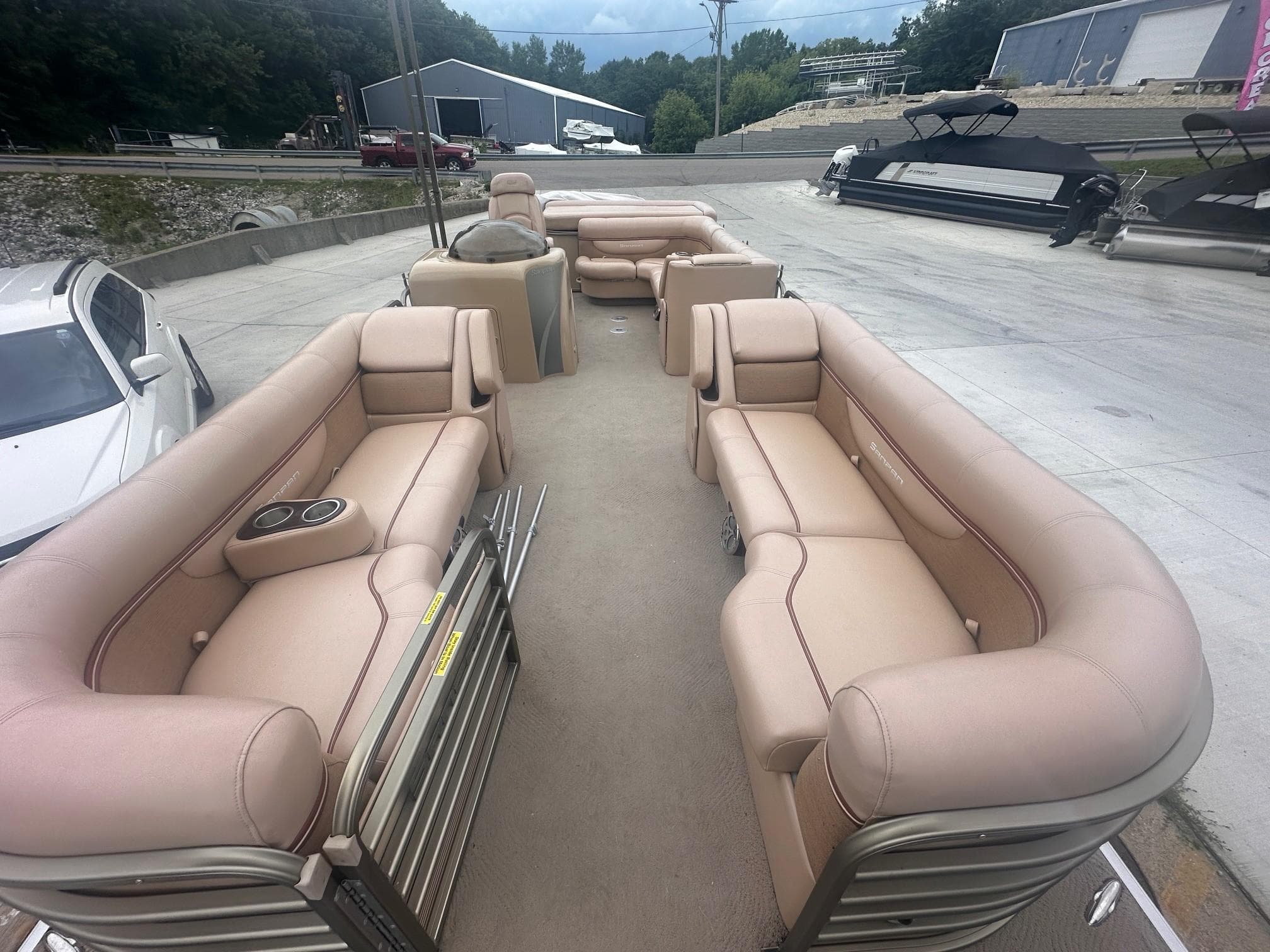 2008 Godfrey Sanpan 2500 RE pontoon boat with beige seating, parked outdoors.