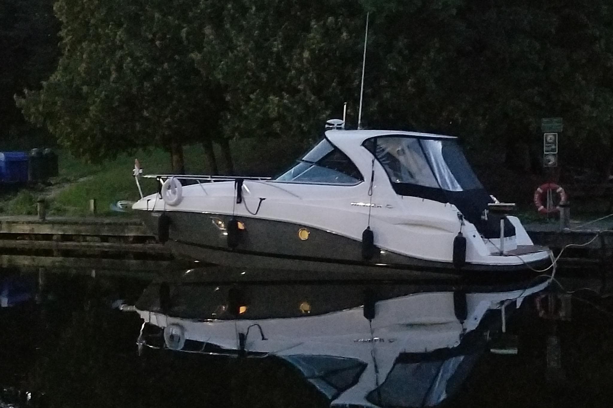 2012 Rinker 310 Express Cruiser docked by a serene lakeside.