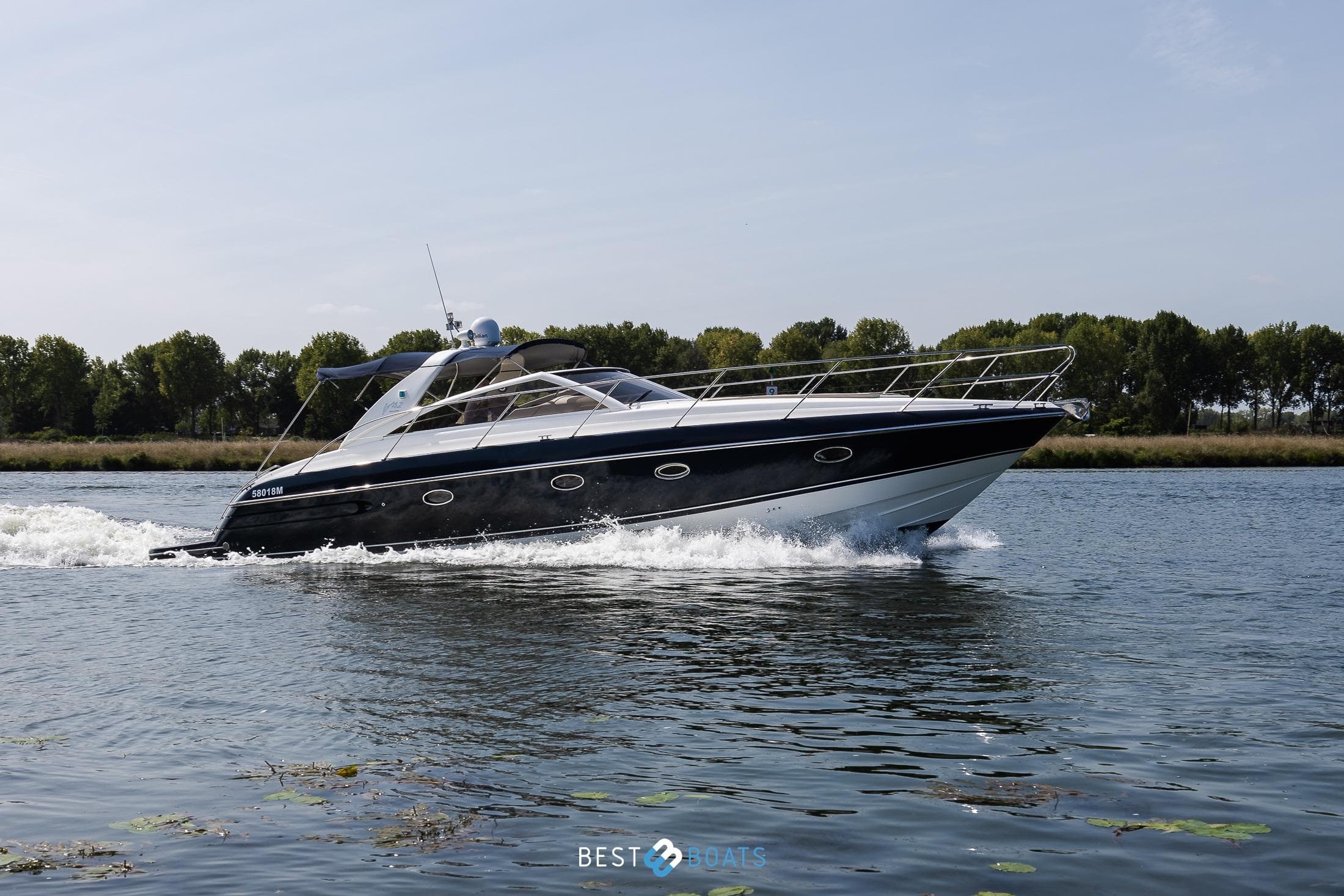 2006 Princess V42 yacht cruising on a calm river with trees in the background.