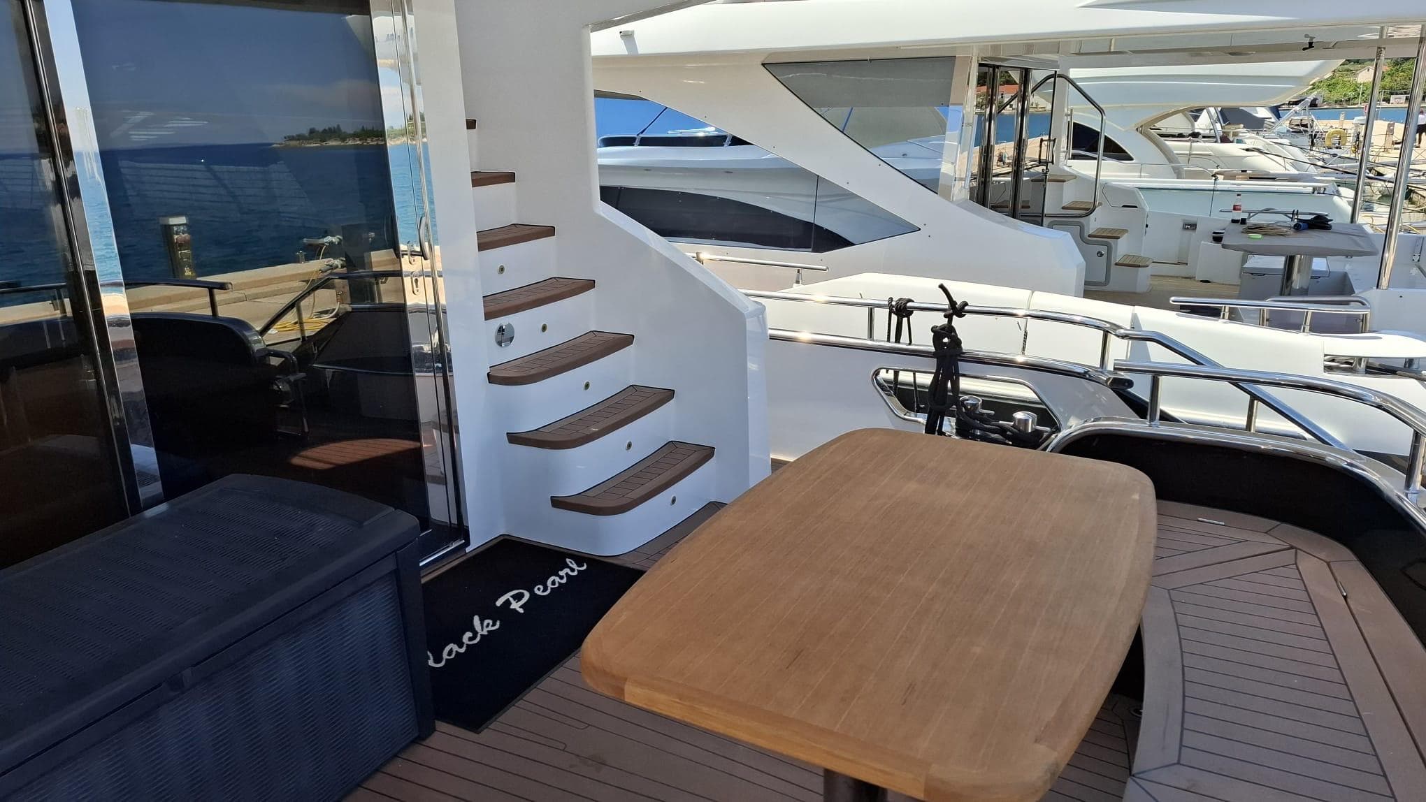 Luxurious Van der Heijden Superior 2000 yacht deck with wooden table, stairs, and ocean view.