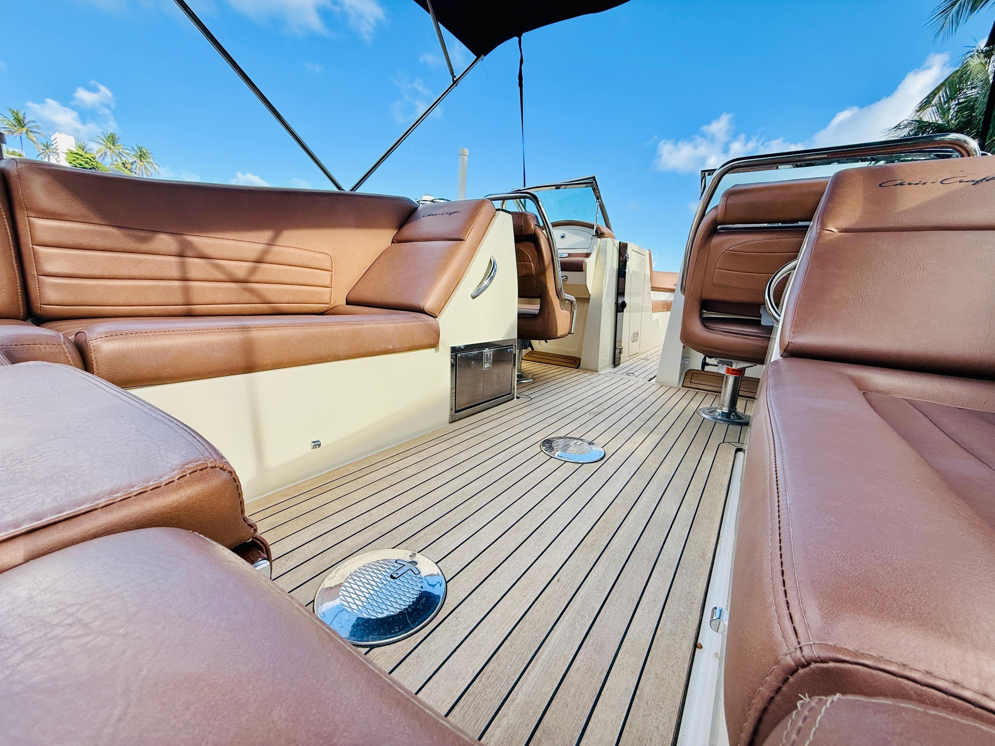 2015 Chris-Craft Launch 32 interior with brown leather seats and teak flooring under blue sky.