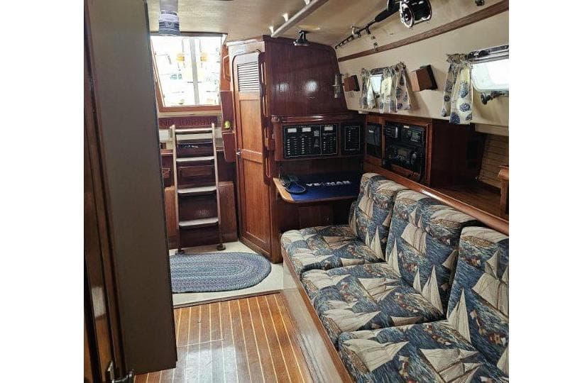 Interior of 1999 Island Packet 350 sailboat with nautical-themed upholstery and wooden finishes.