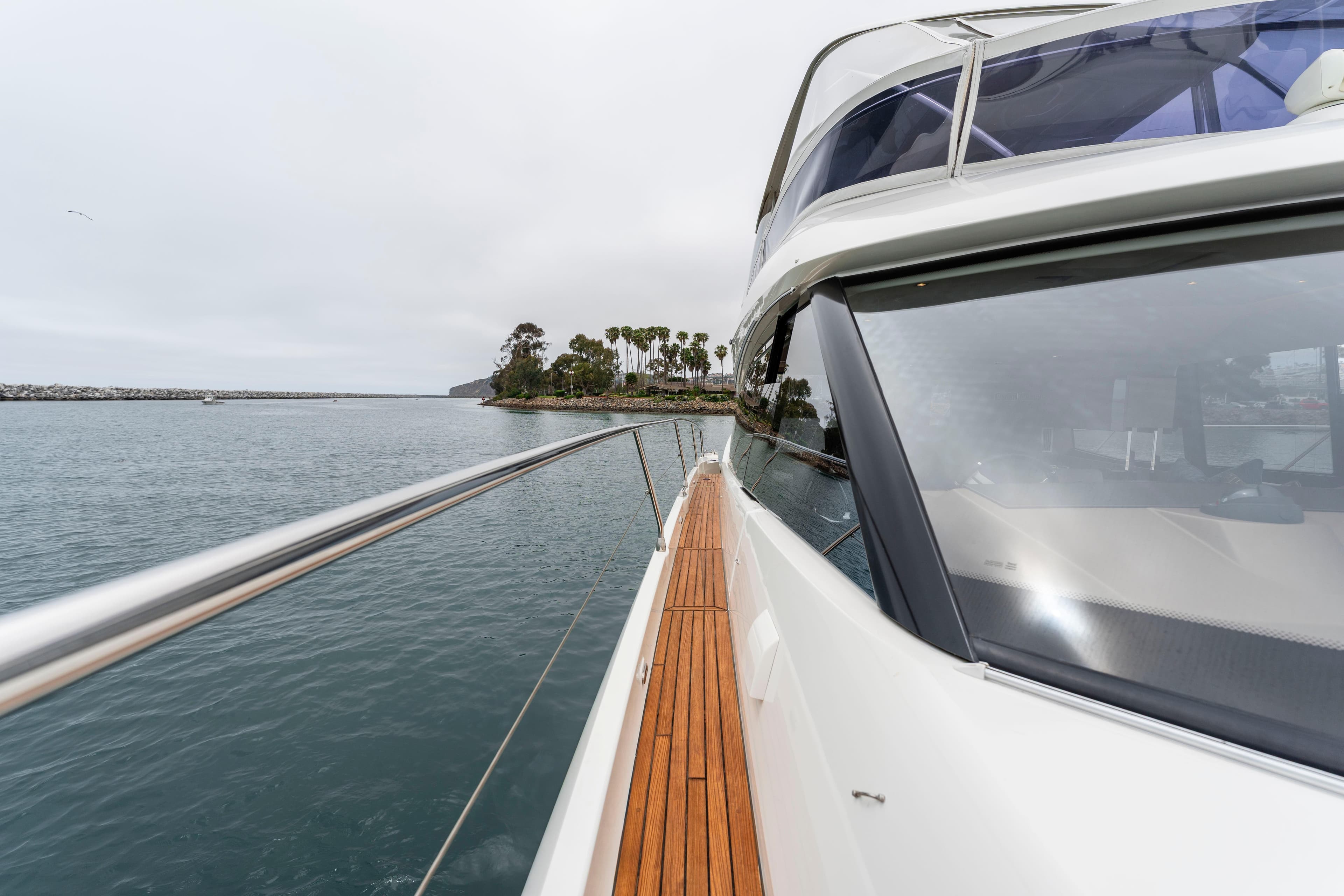 2018 Prestige 560 yacht cruising near a scenic coastline with palm trees.