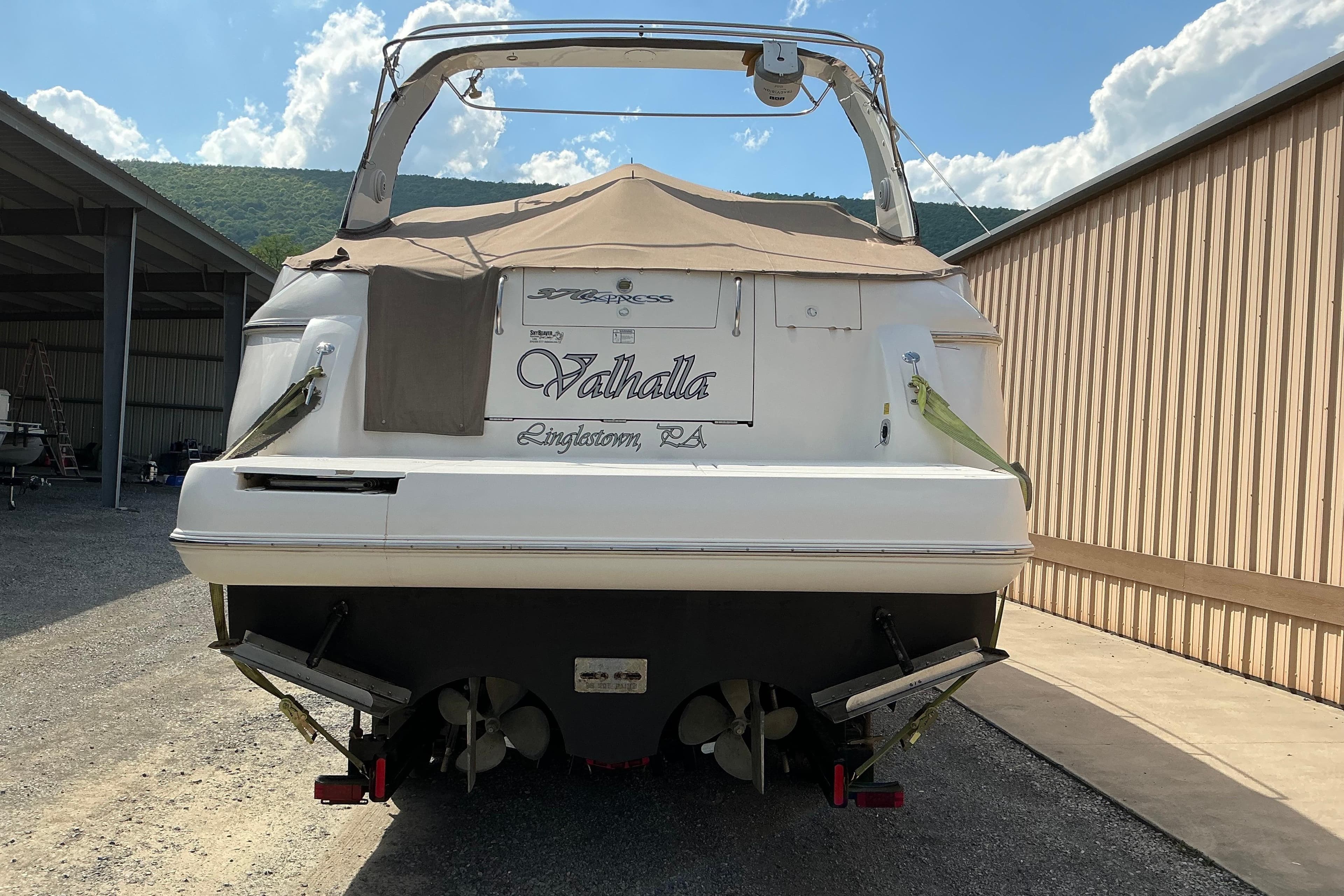 2005 Cruisers Yachts 370 Express boat docked, rear view with cover, sunny day.