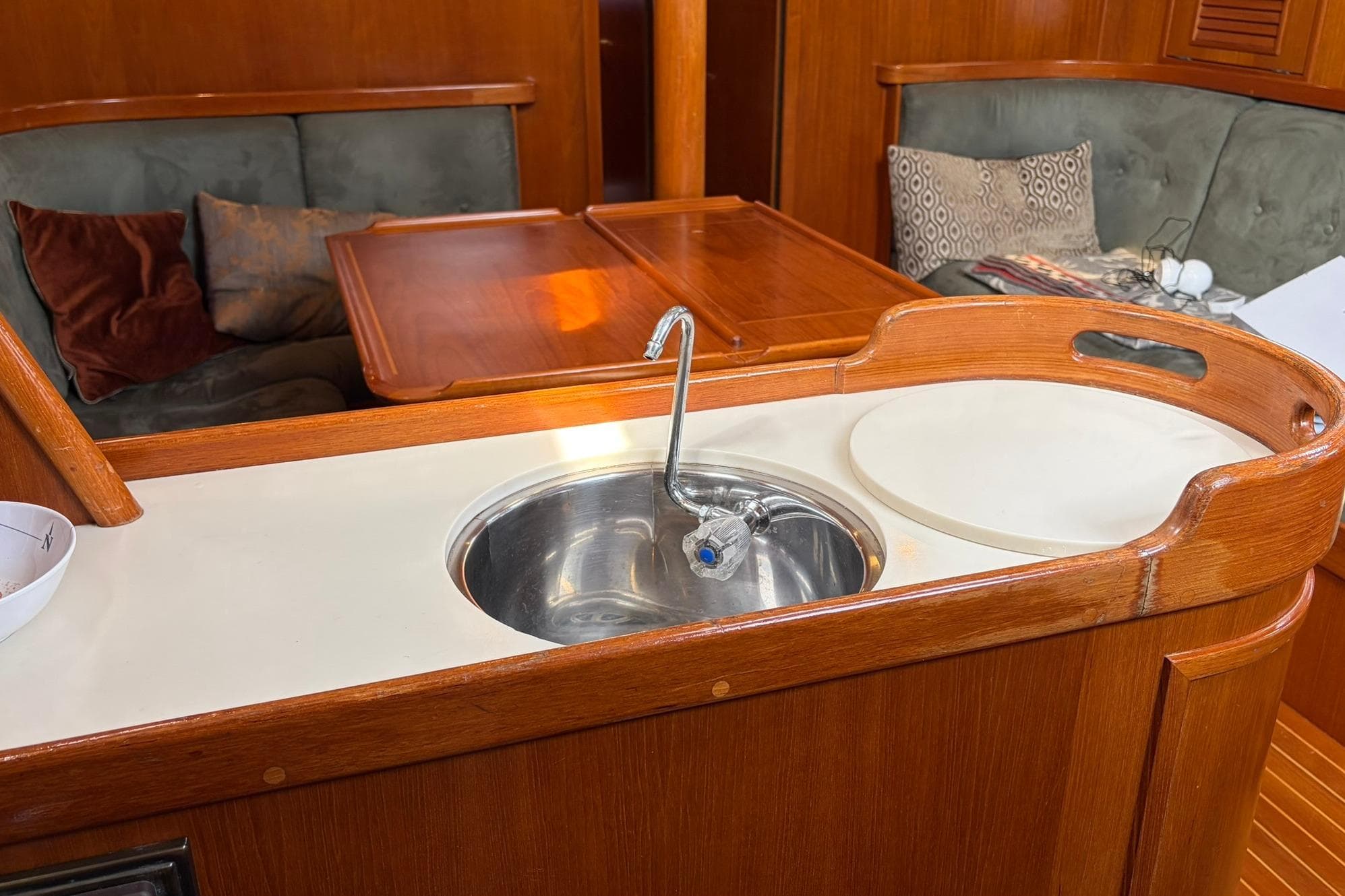 Cozy yacht interior with wooden finish, featuring a compact sink and seating area.