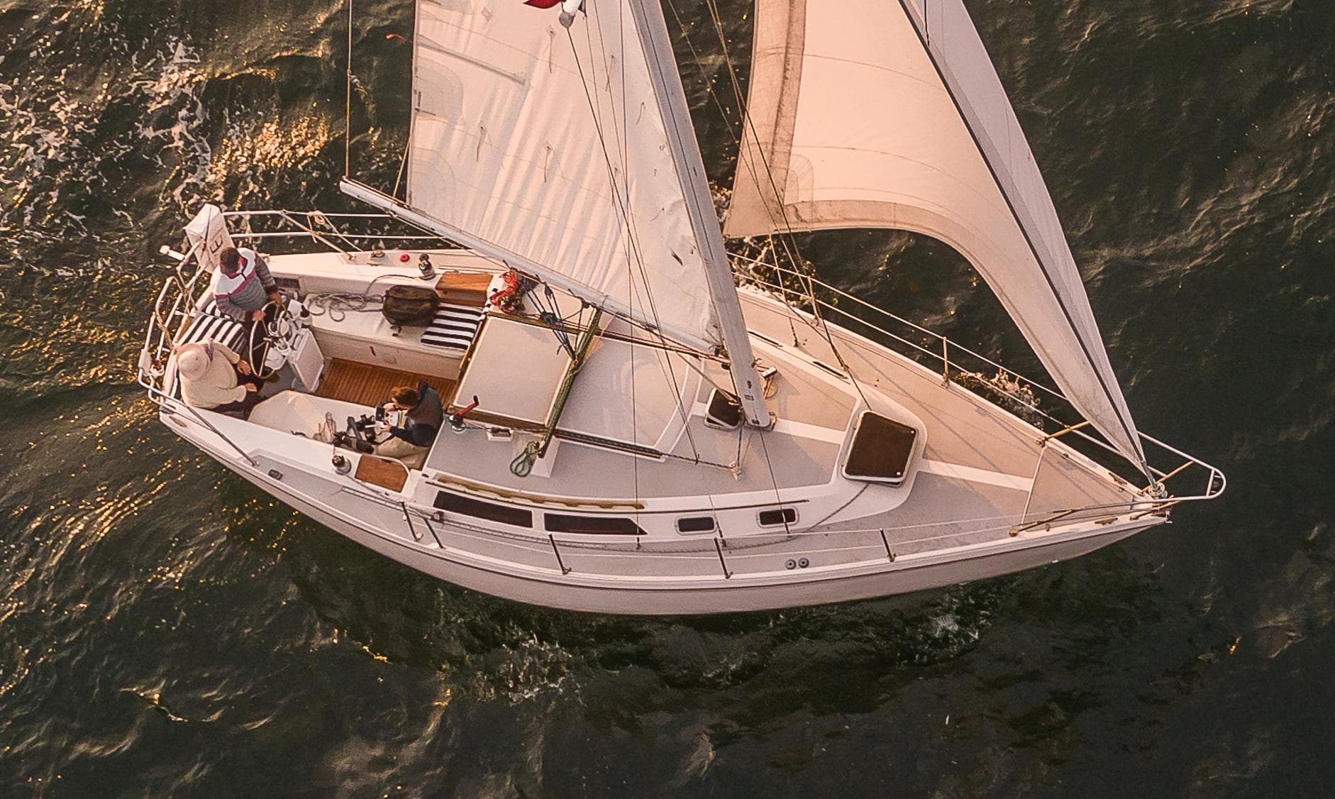 1988 Catalina 30 MkII sailboat navigating ocean waters at sunset.