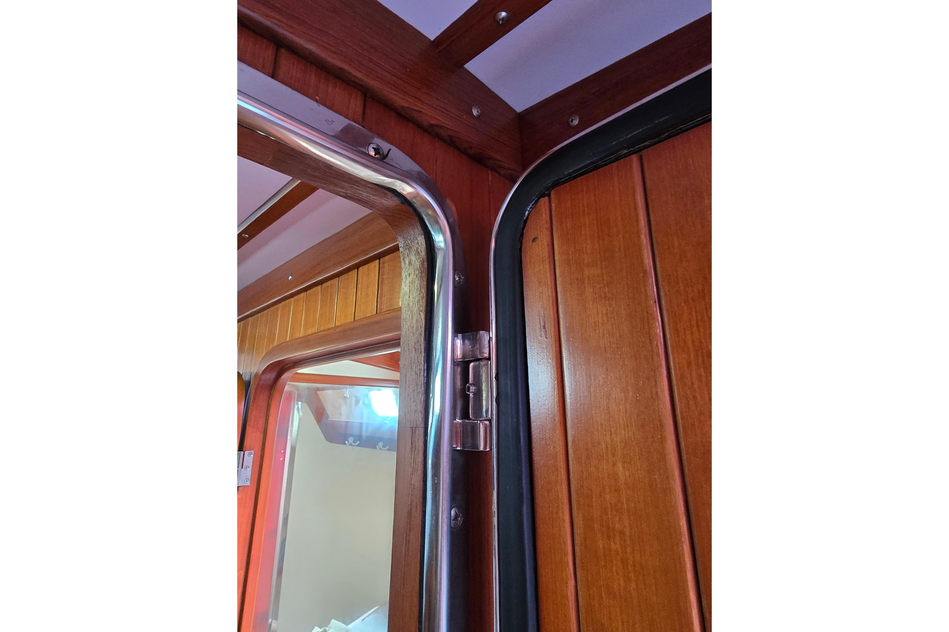 Interior view of 2006 Tayana Vancouver 42 yacht, showcasing wooden door and metal frame.