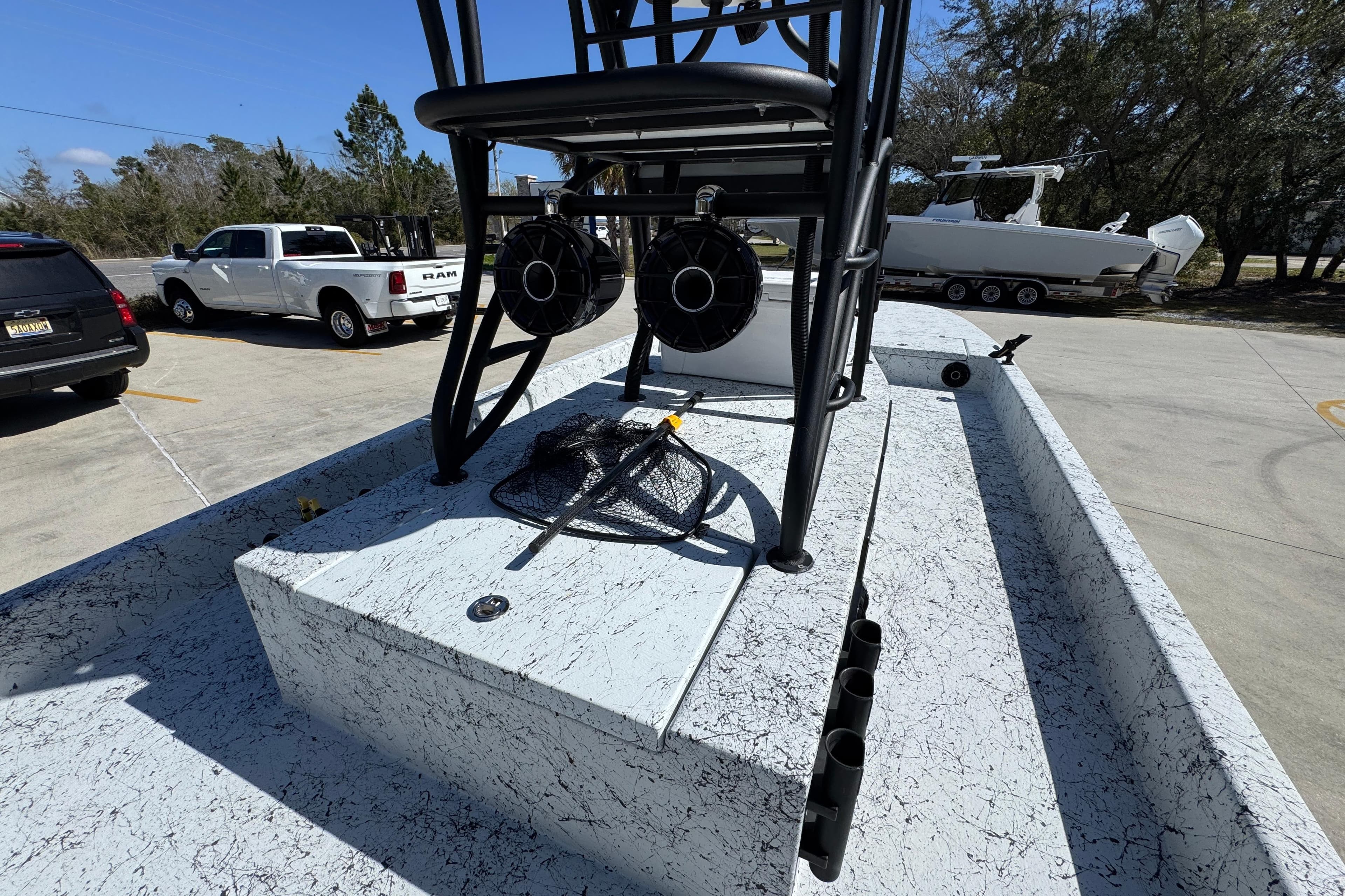 2023 Dek Kat 27 Trilogy boat with fishing gear on deck, parked near vehicles.