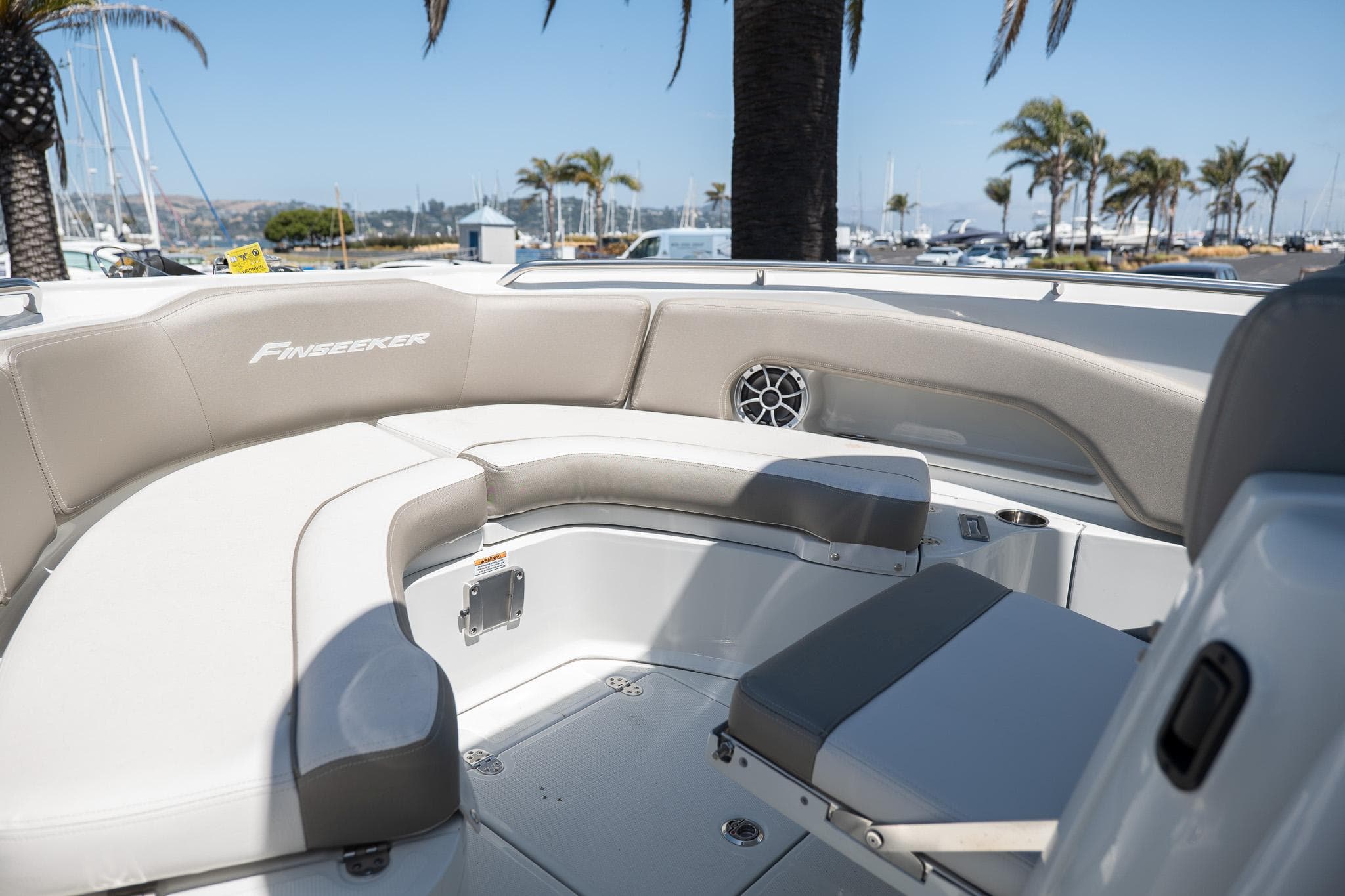 2023 Finseeker 230 CC boat interior with cushioned seating and palm trees in the background.