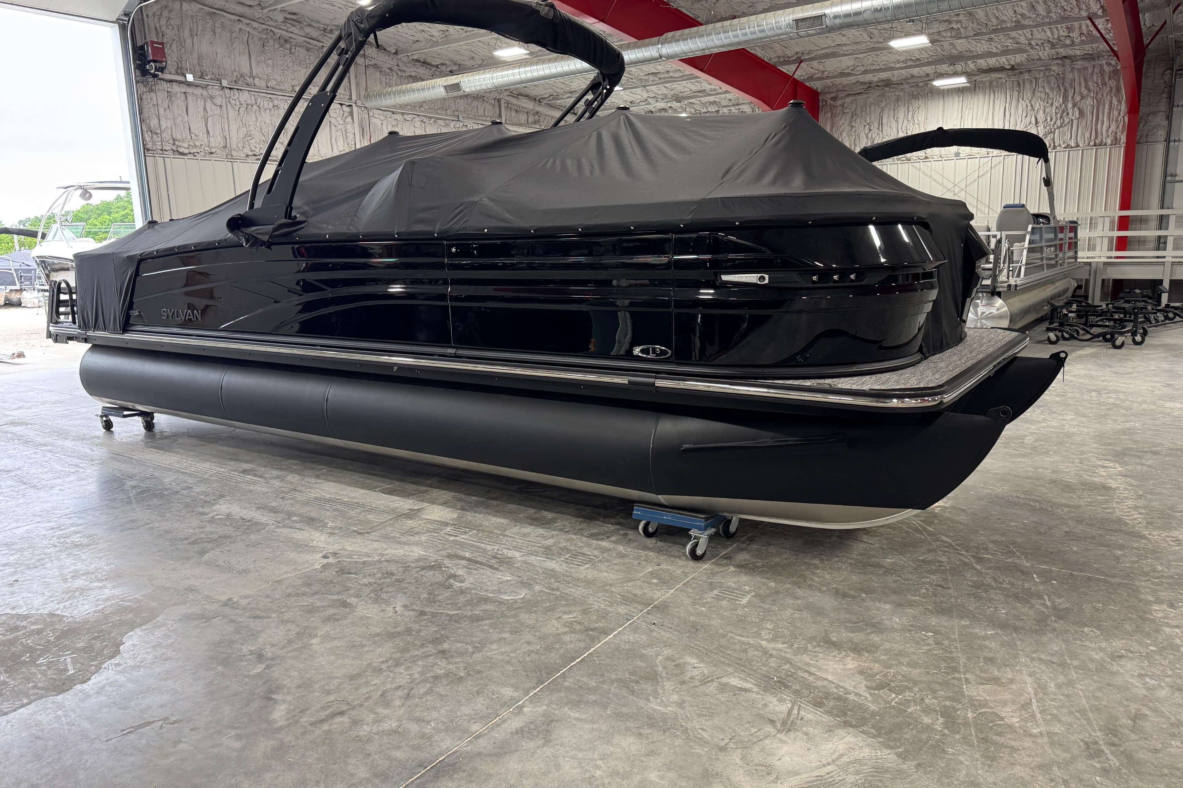 2026 Sylvan L5 DLZ pontoon boat in a showroom, covered and ready for display.