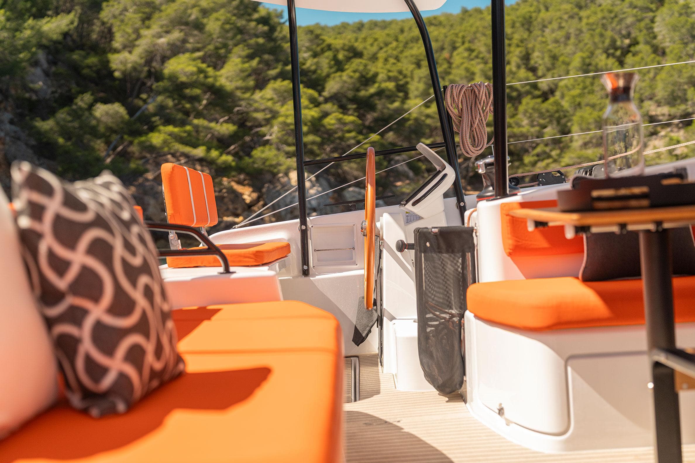 Luxurious 2026 Excess 13 yacht interior with vibrant orange seating and scenic forest backdrop.