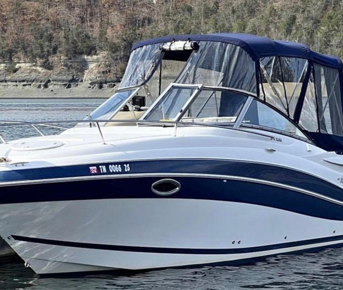 2008 Four Winns V258 boat on calm water with forested shoreline.
