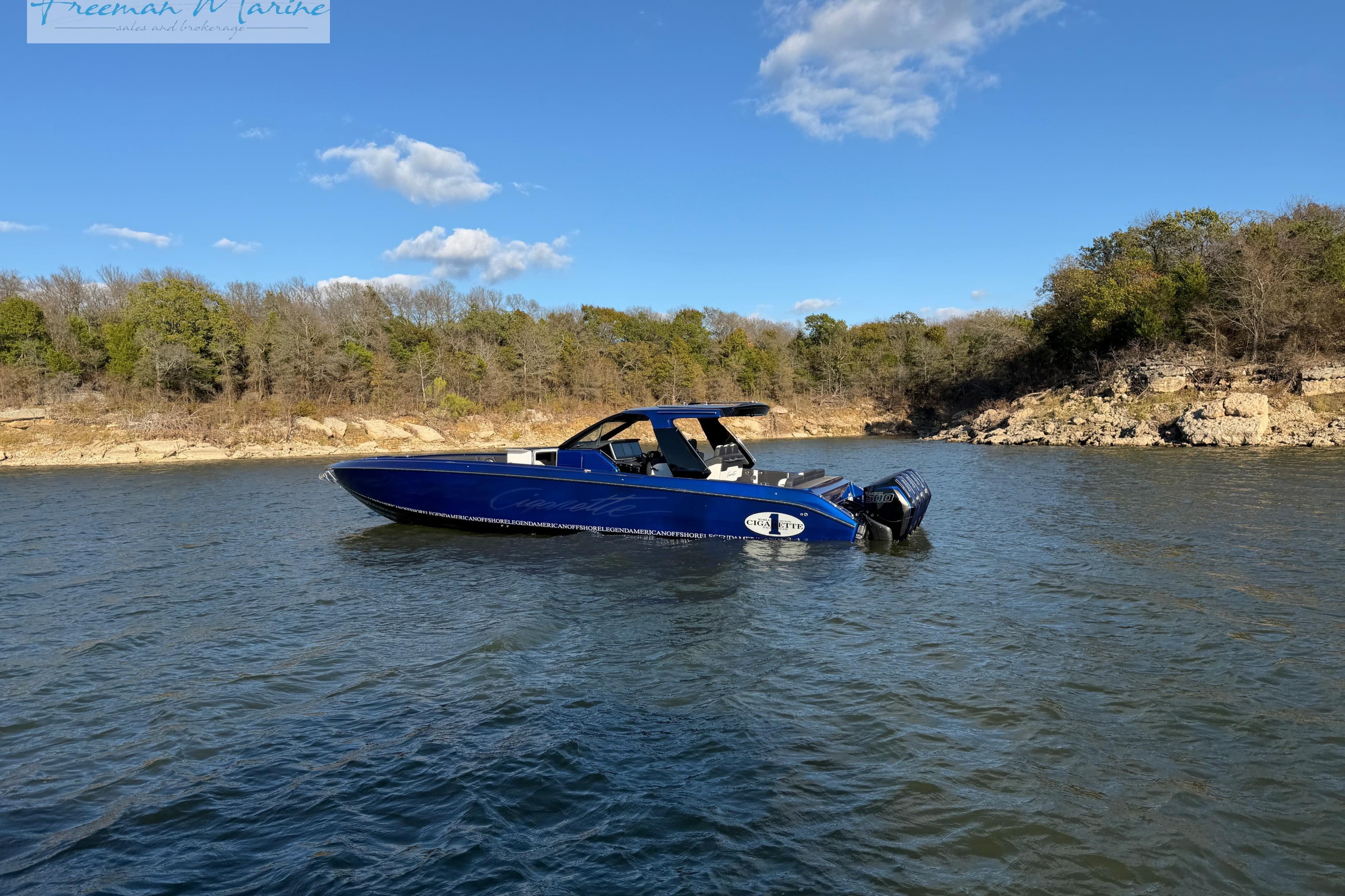 2024 Cigarette 41' Nighthawk boat on a serene lake with a wooded shoreline.