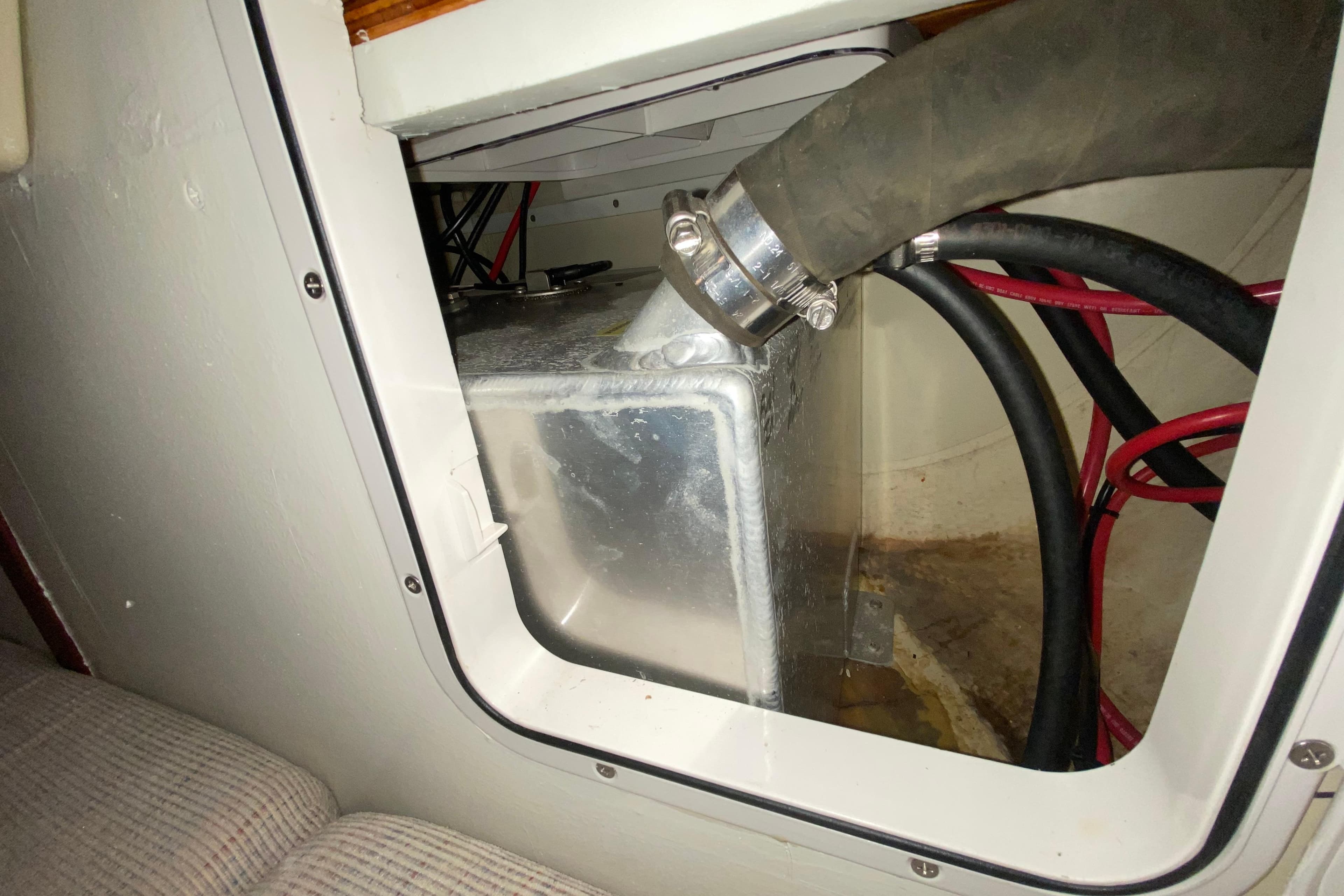 Interior view of a 1995 Hunter 33.5 sailboat showing a metal tank and hoses.
