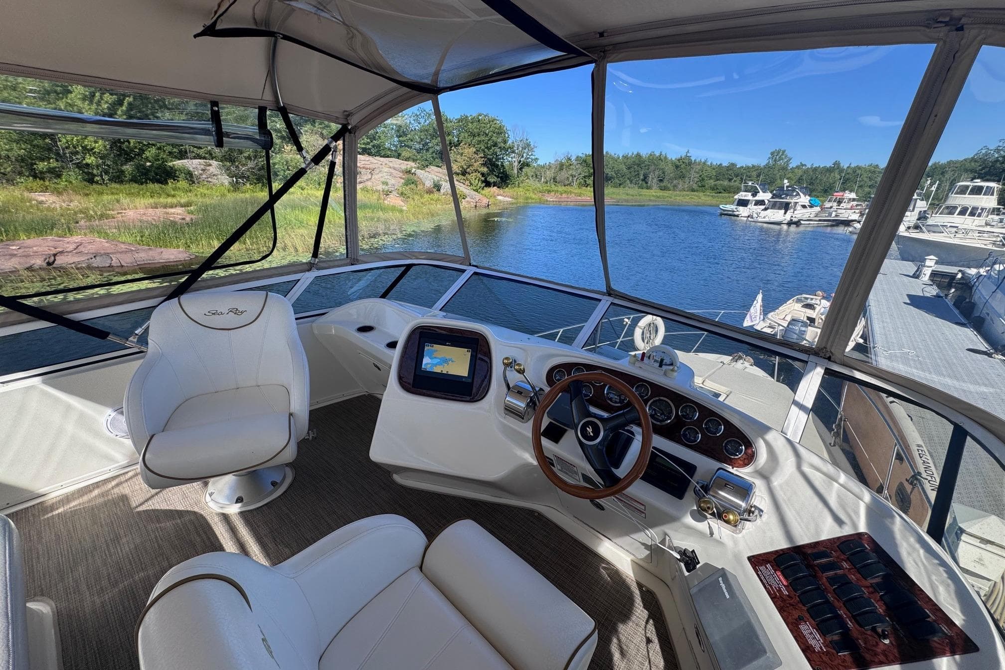 Cockpit view of 2000 Sea Ray 380 Aft Cabin yacht, featuring steering wheel and navigation system.
