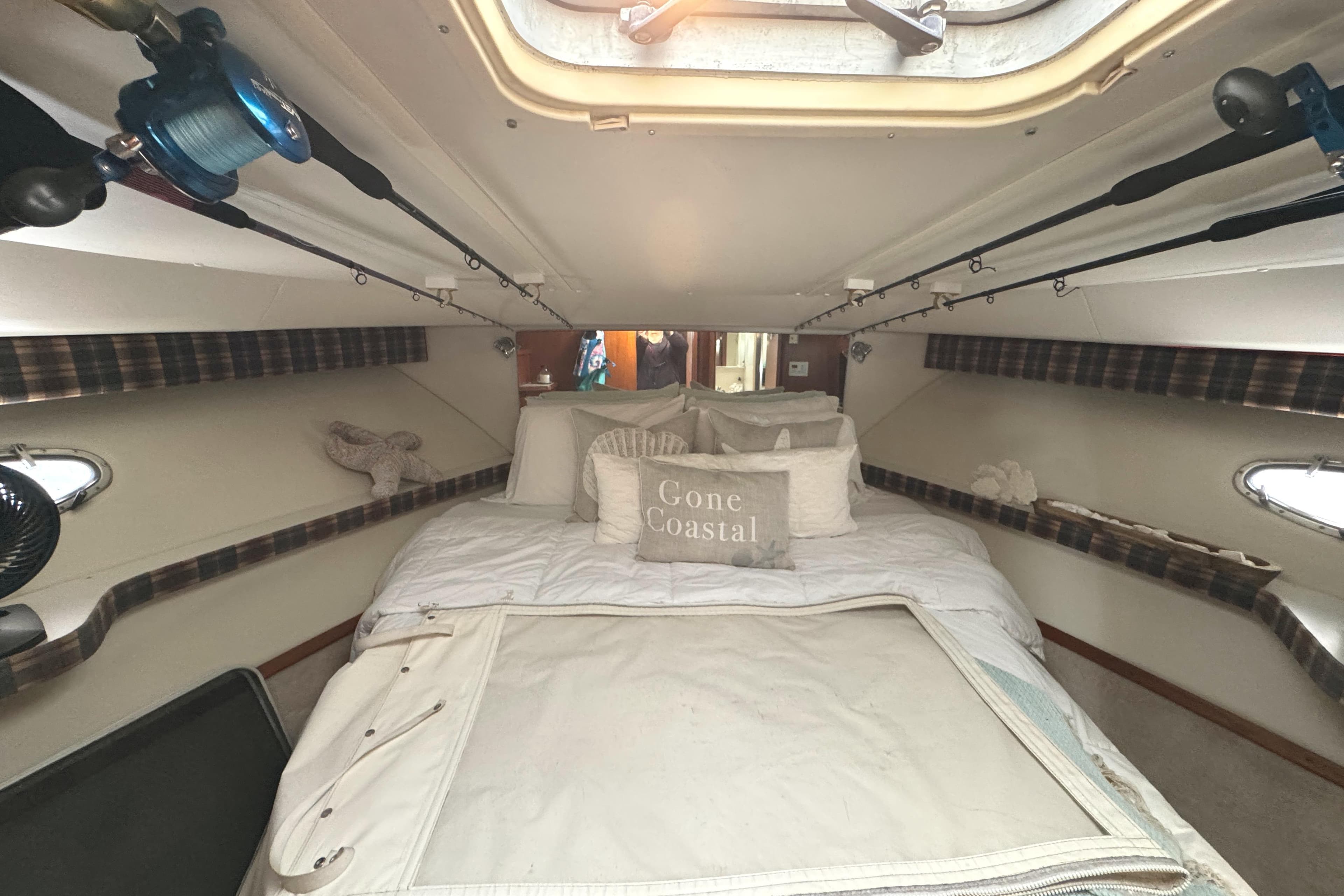 Cozy cabin interior of 1998 Tiara Yachts 4100 Open with plush bedding and fishing rods.
