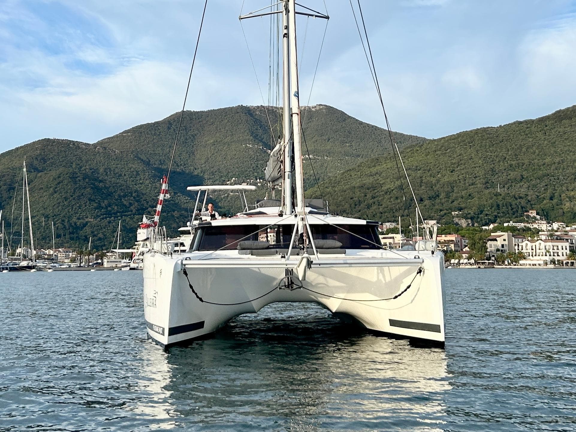 2021 Fountaine Pajot Saona 47 catamaran on water with scenic mountain backdrop.