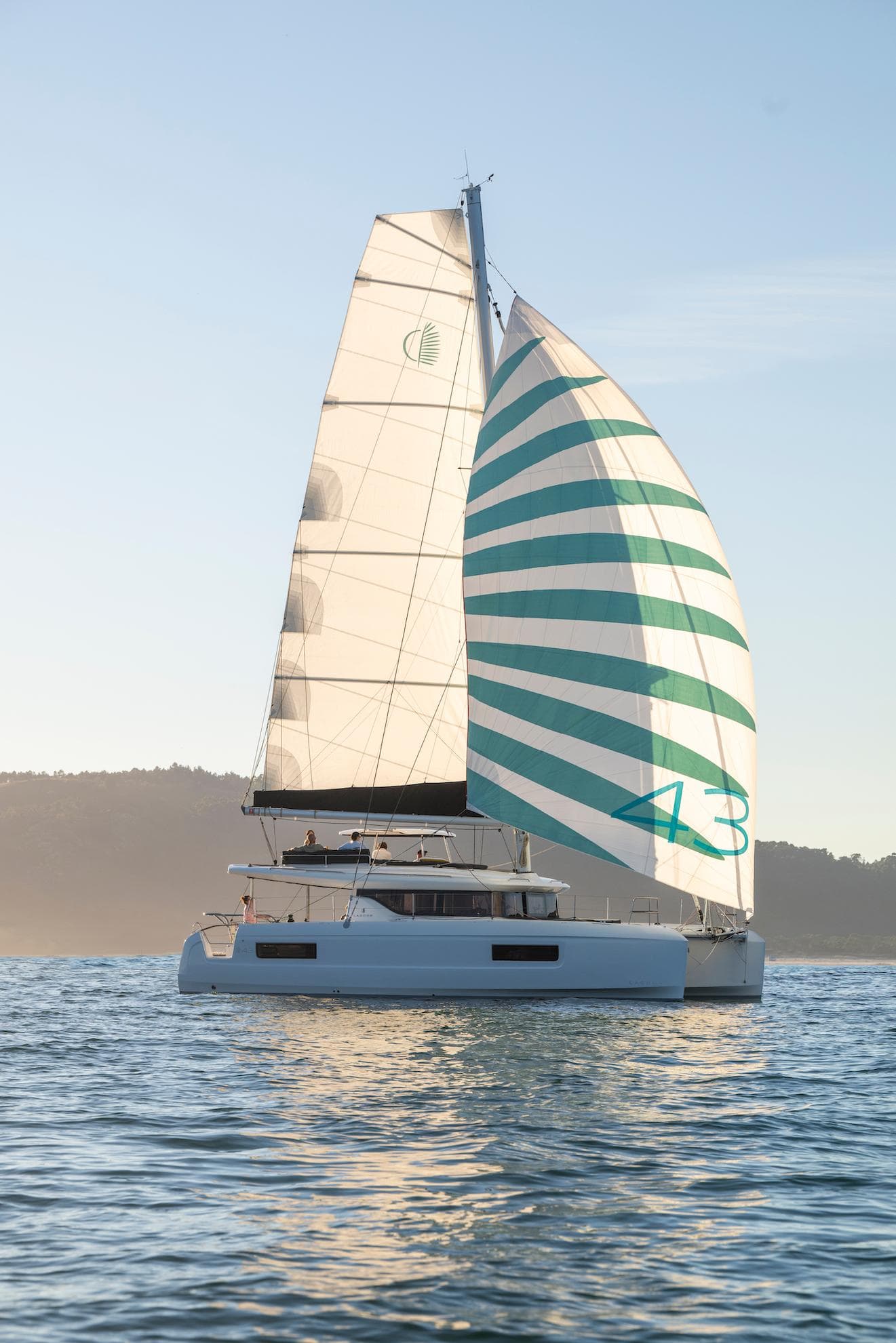 2025 Lagoon 43 catamaran sailing on calm waters at sunset.