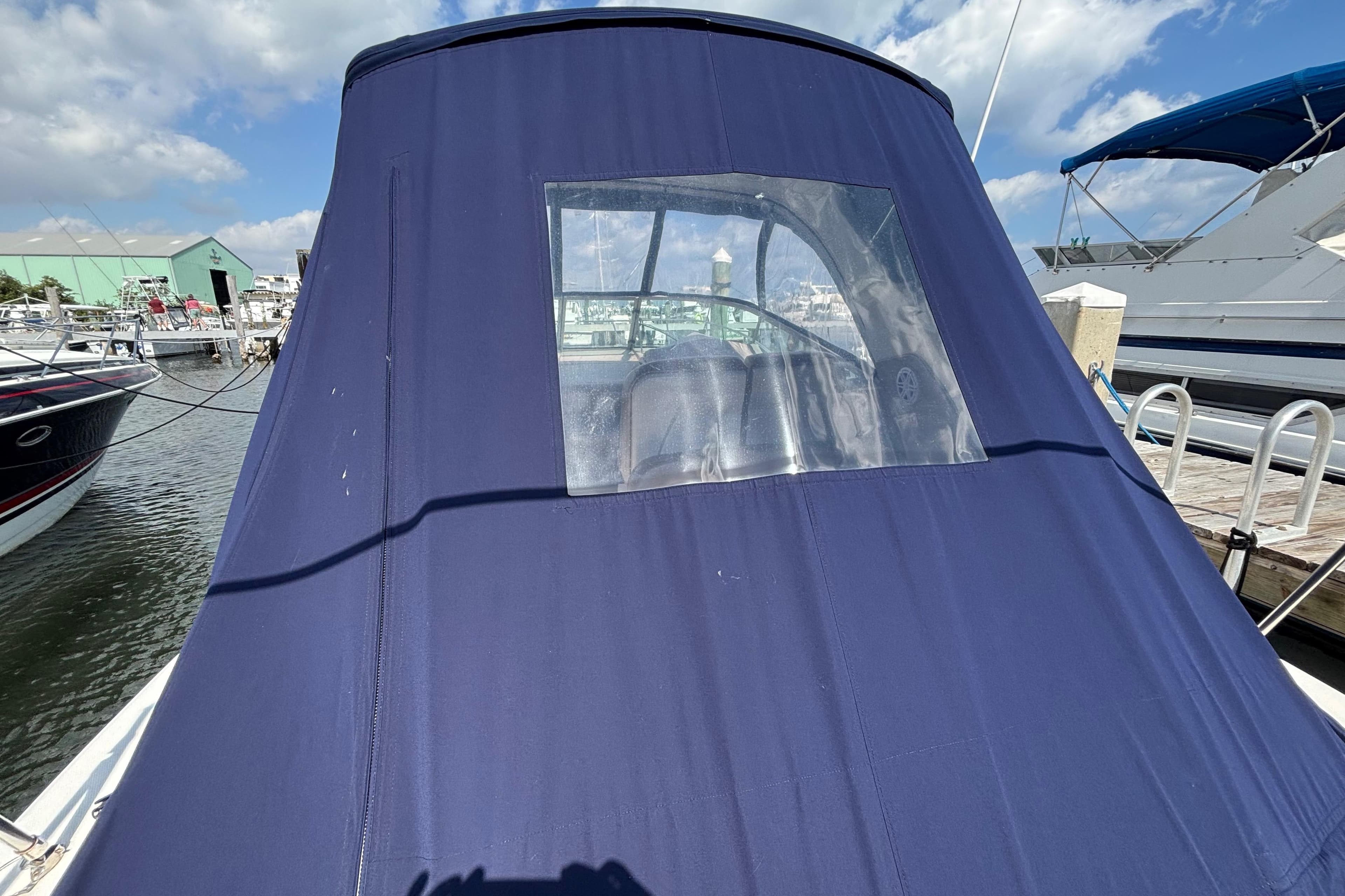 2009 Sea Ray Sundancer 310 with blue canvas cover at marina dock.