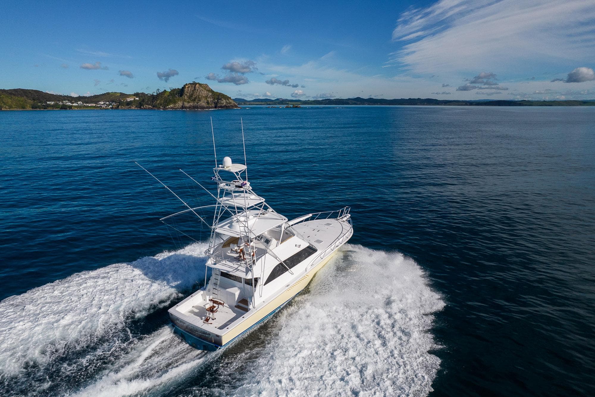 2003 Viking 48 Convertible yacht cruising on open water, scenic coastal backdrop.