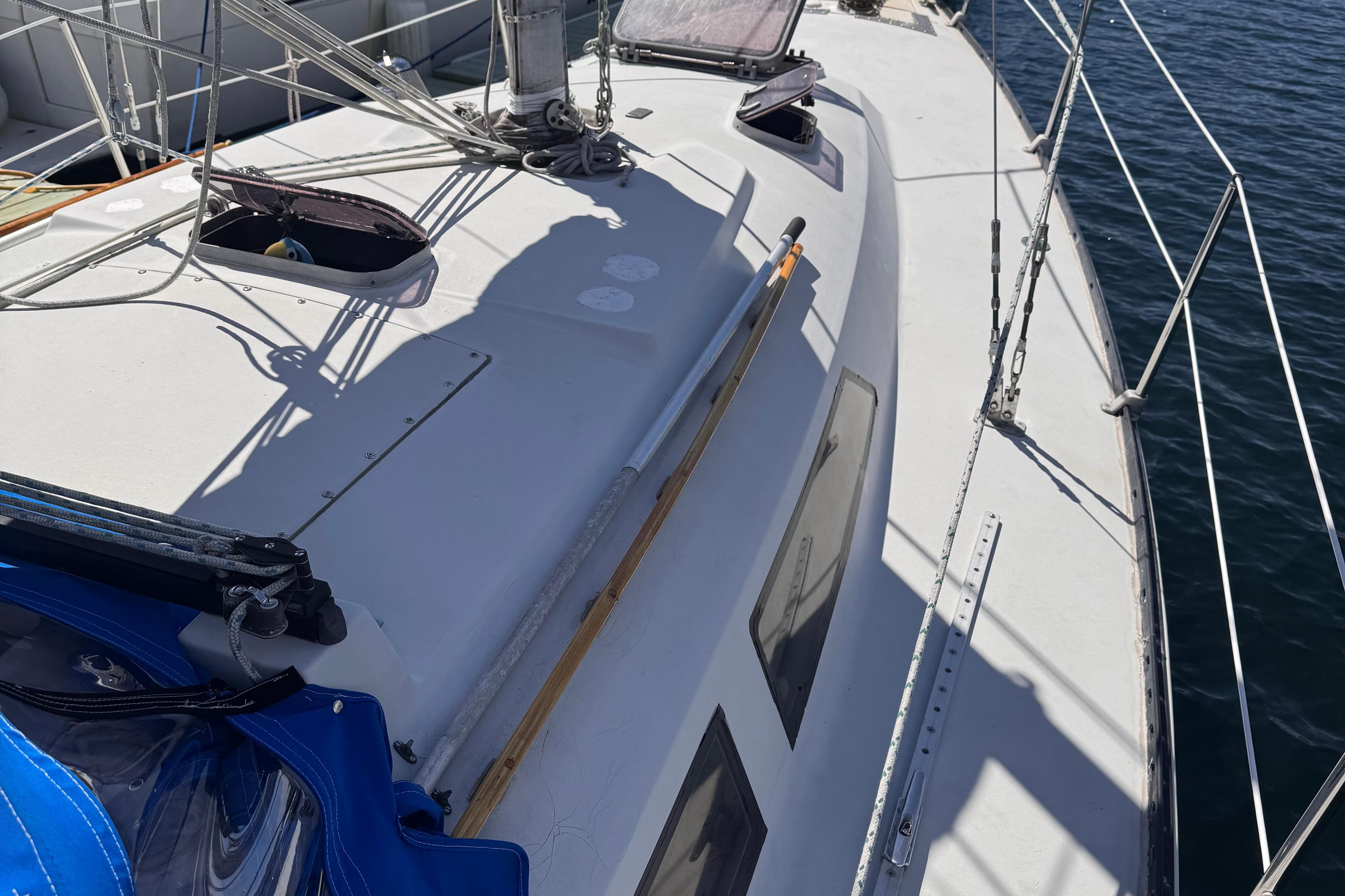 1983 C&C 32 sailboat deck with rigging and open hatches, docked by the water.