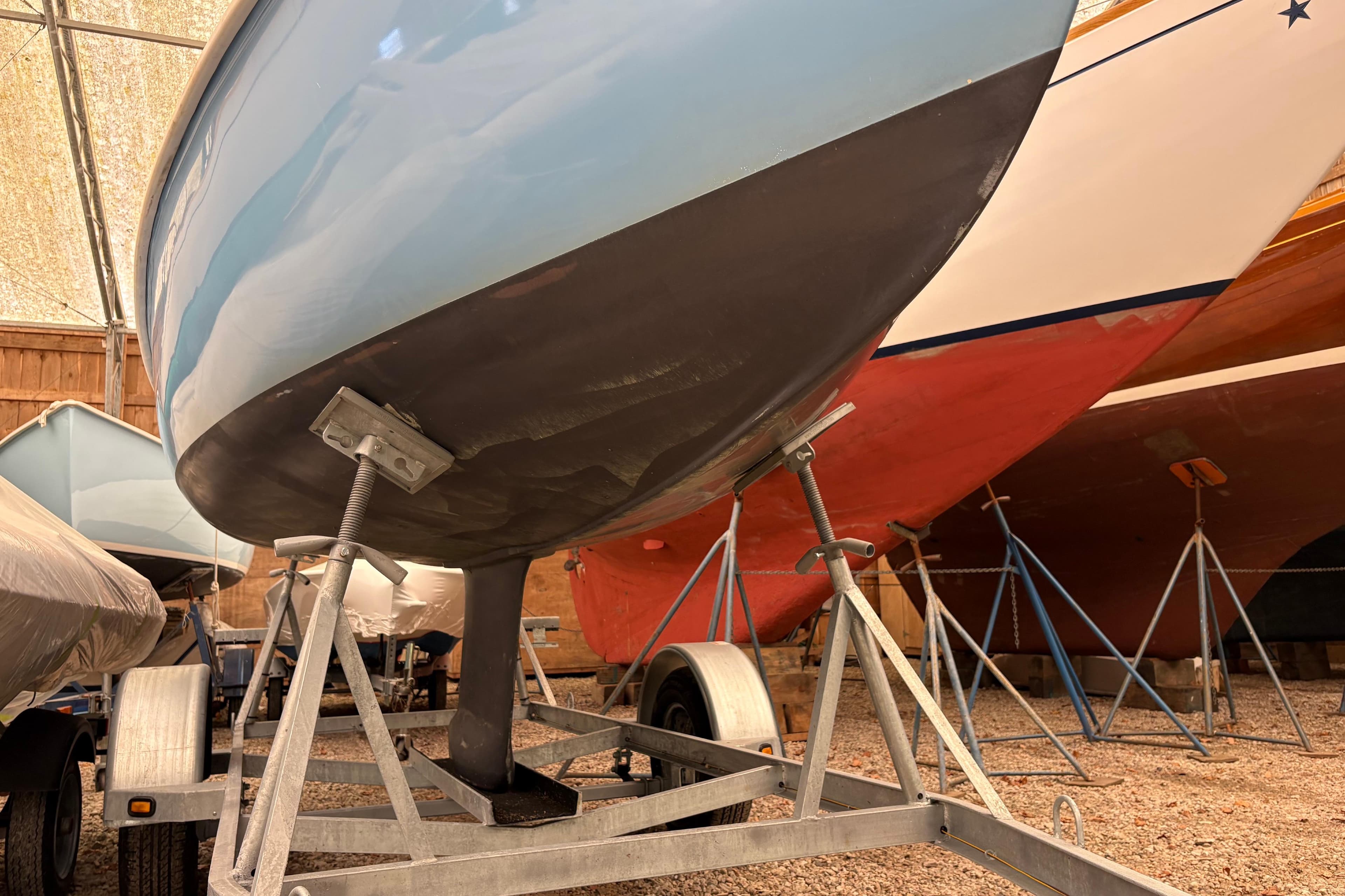 1971 Rhodes 19 sailboat on trailer in storage, showcasing hull and keel.
