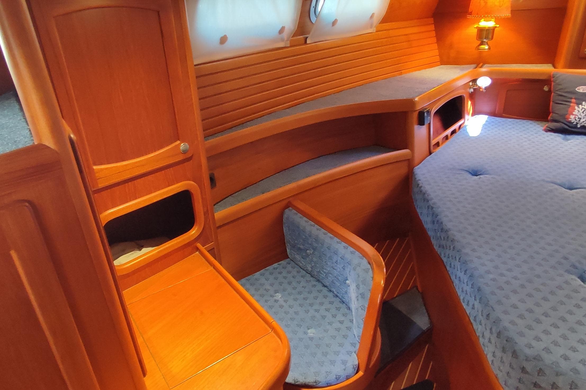 Cozy cabin interior of 1997 Nauticat 42 sailboat with wooden furnishings and blue upholstery.