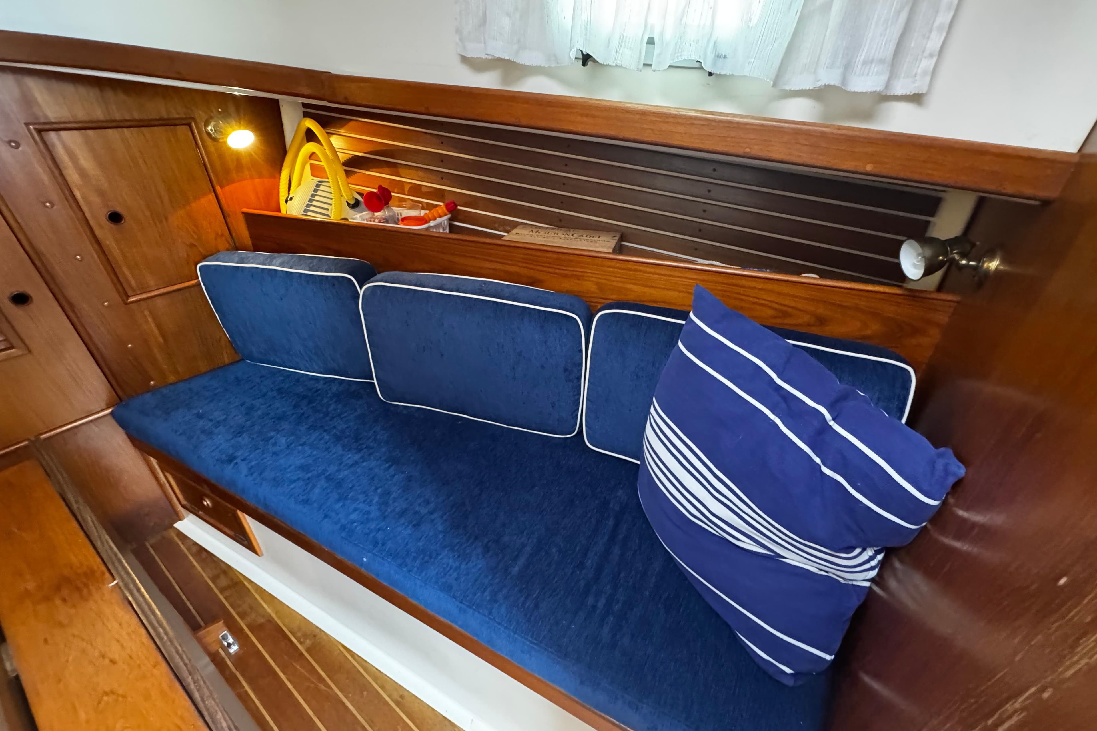 Cozy interior of 1984 Nonsuch 26 Classic sailboat with blue cushions and striped pillow.