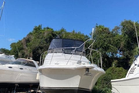 1998 Carver 380 Santego yacht docked, surrounded by trees and clear blue sky.
