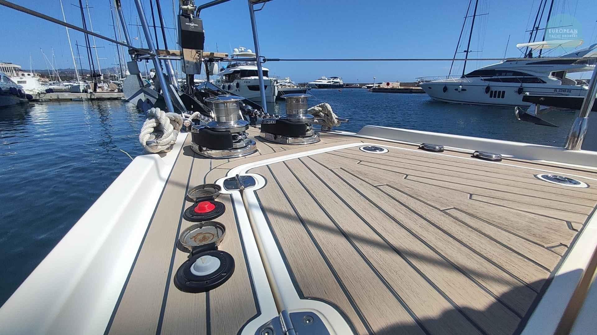Deck view of a 2017 Amel 55 yacht docked in a marina under clear blue skies.
