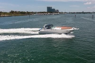 1997 Sea Ray 400 Express Cruiser speeding on open water near coastline.