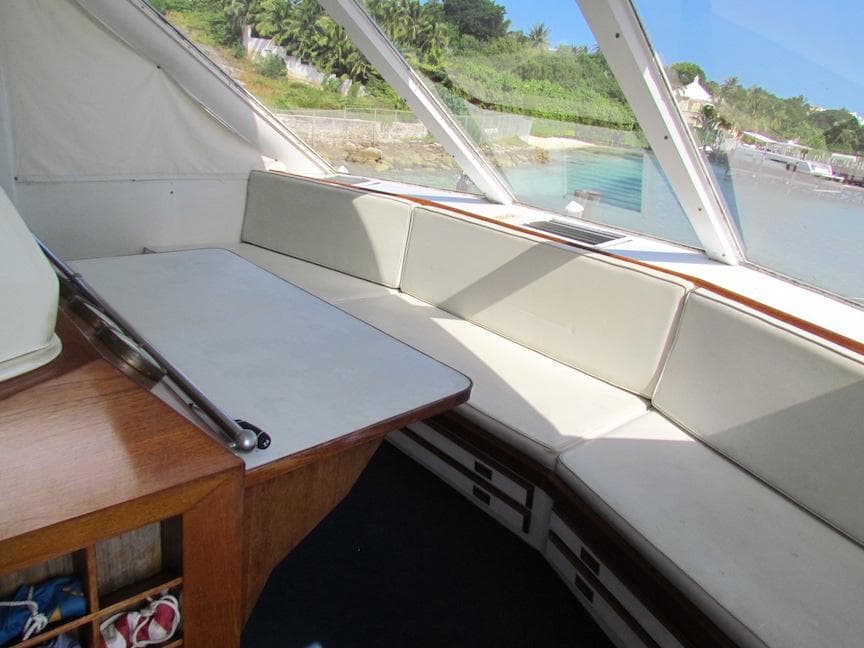 Interior of 1972 Hargrave 67 Motor Yacht with white seating and wooden table.