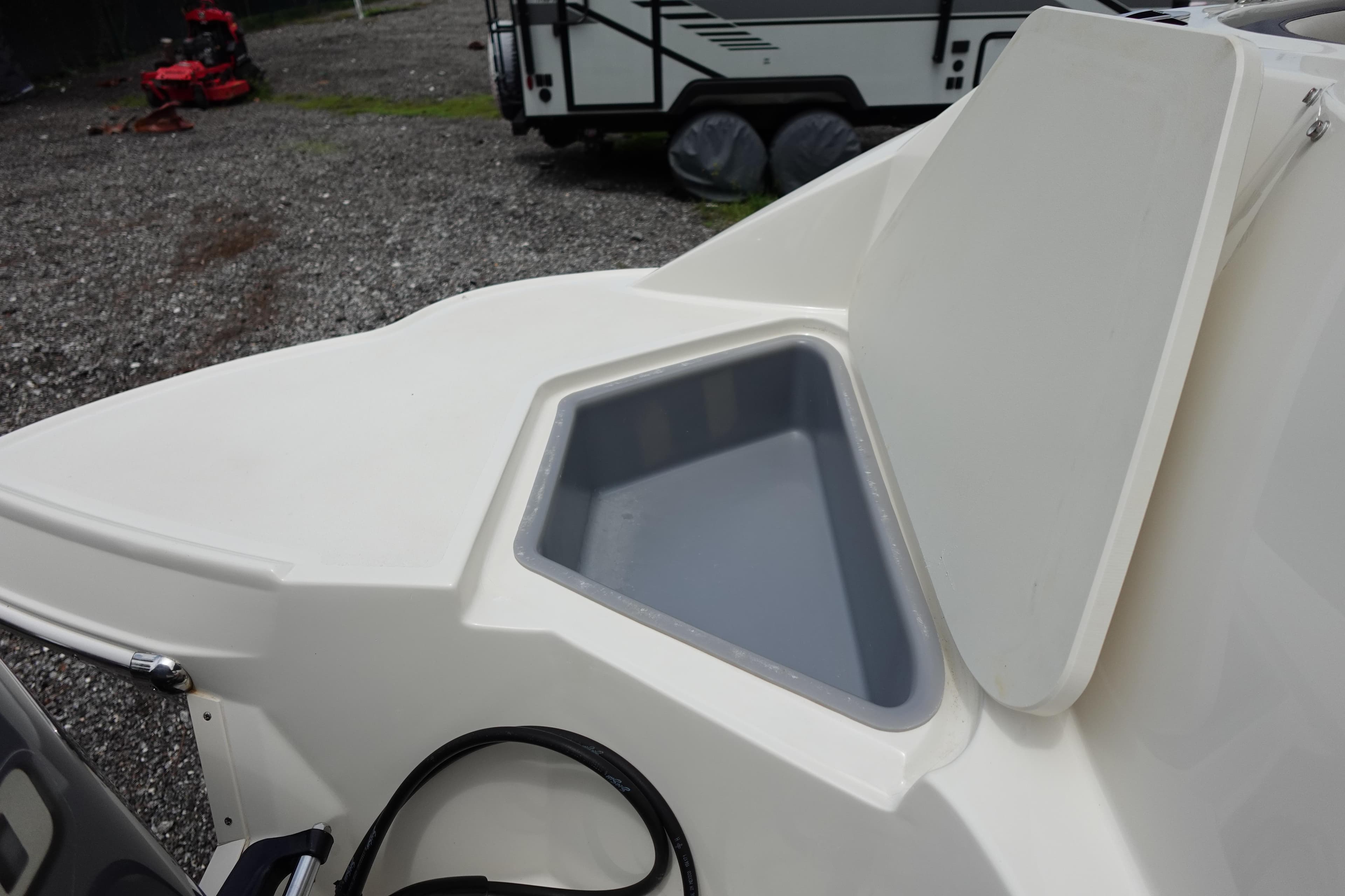 2022 Stingray 231 DC boat storage compartment with open lid, gravel background.