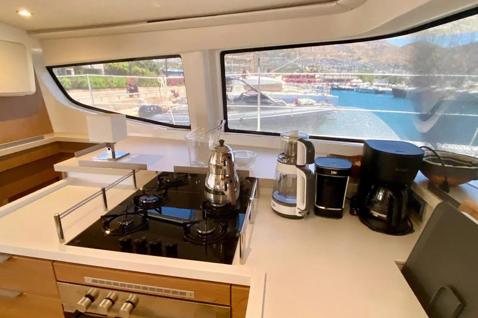 Modern kitchen inside a 2024 Bali 4.4 yacht, featuring appliances and scenic marina view.