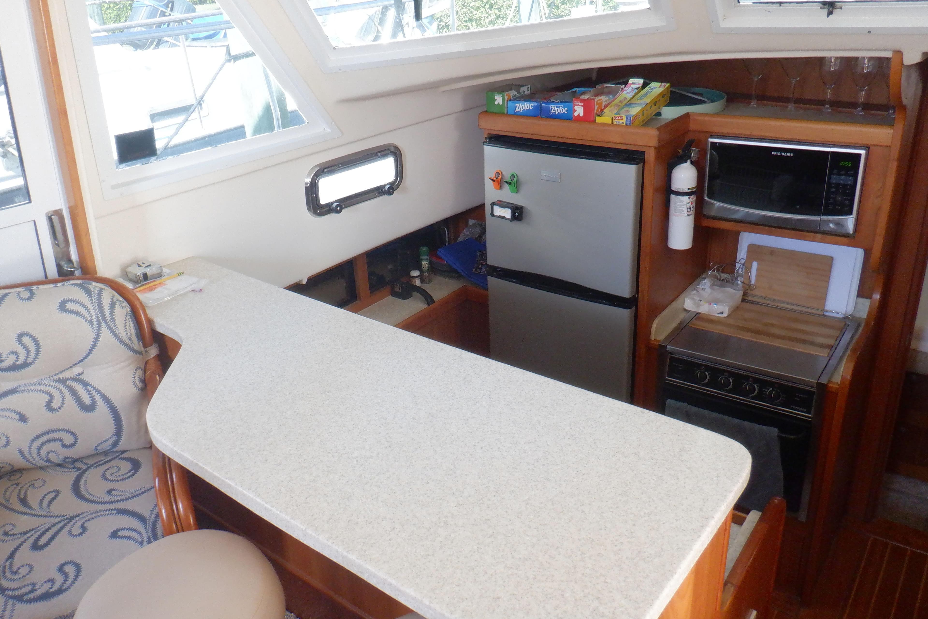 2002 Mainship 430 Trawler kitchen with countertop, fridge, microwave, and stove.