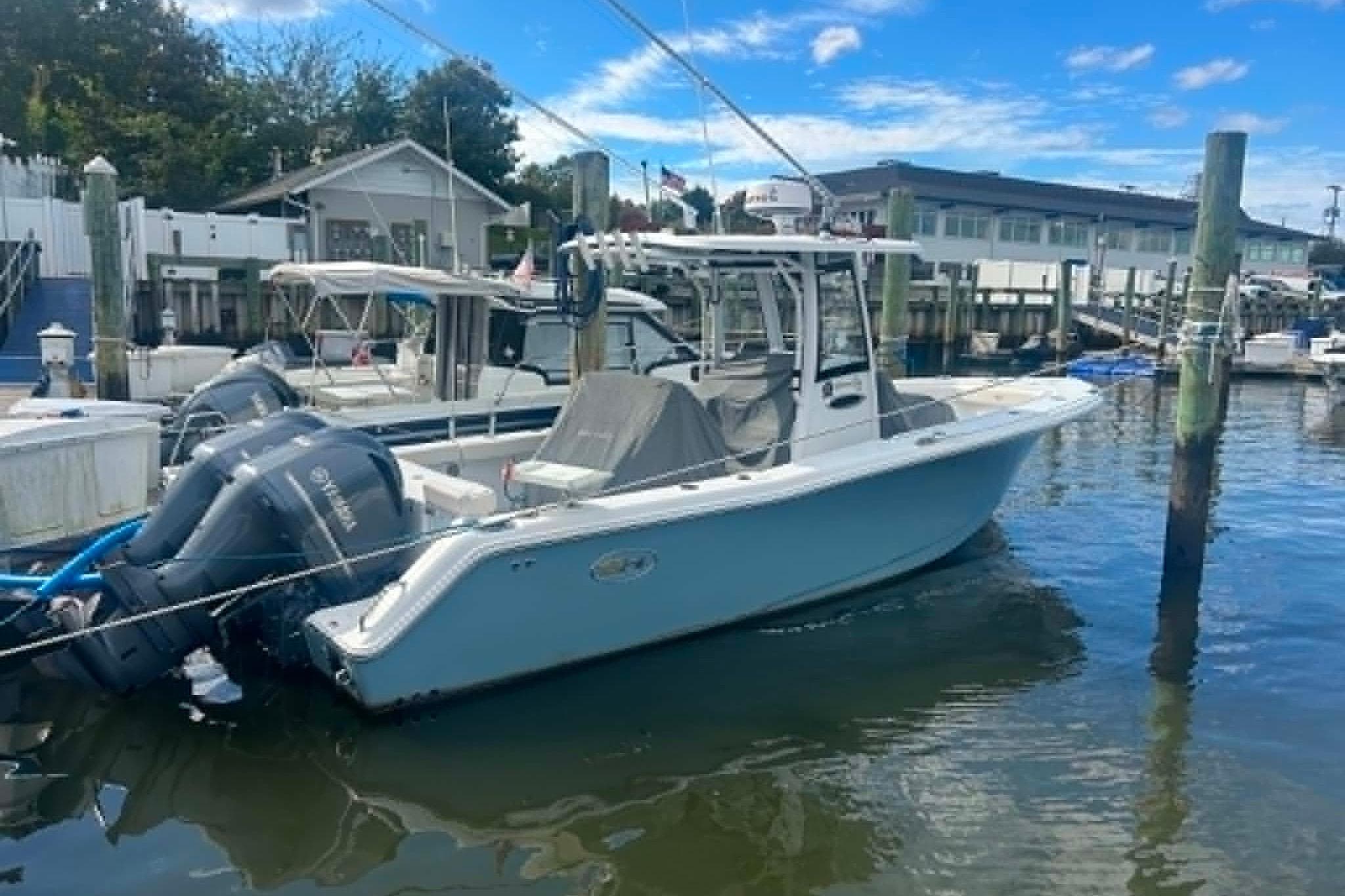 2021 Sea Hunt Gamefish 27 Coffin Box boat docked at marina under blue sky.
