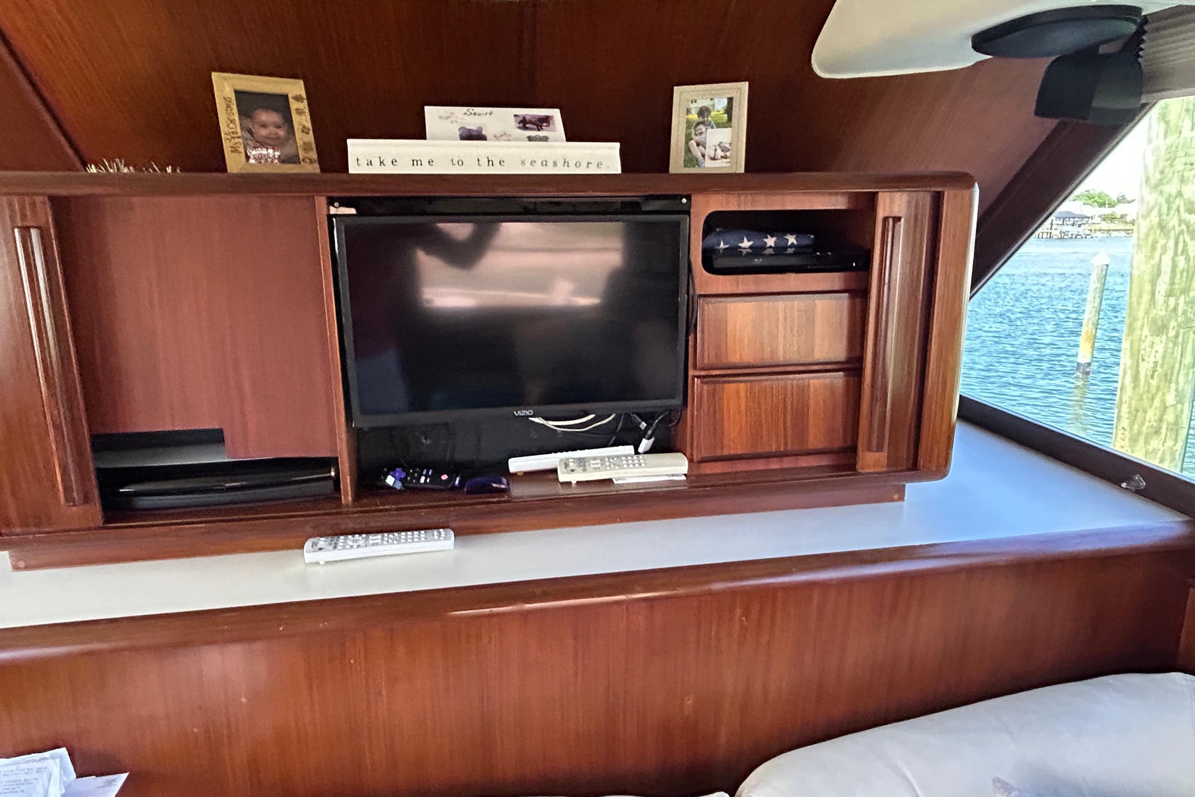 Interior of 1989 Hatteras 45 Convertible yacht with wooden cabinetry and a mounted TV.