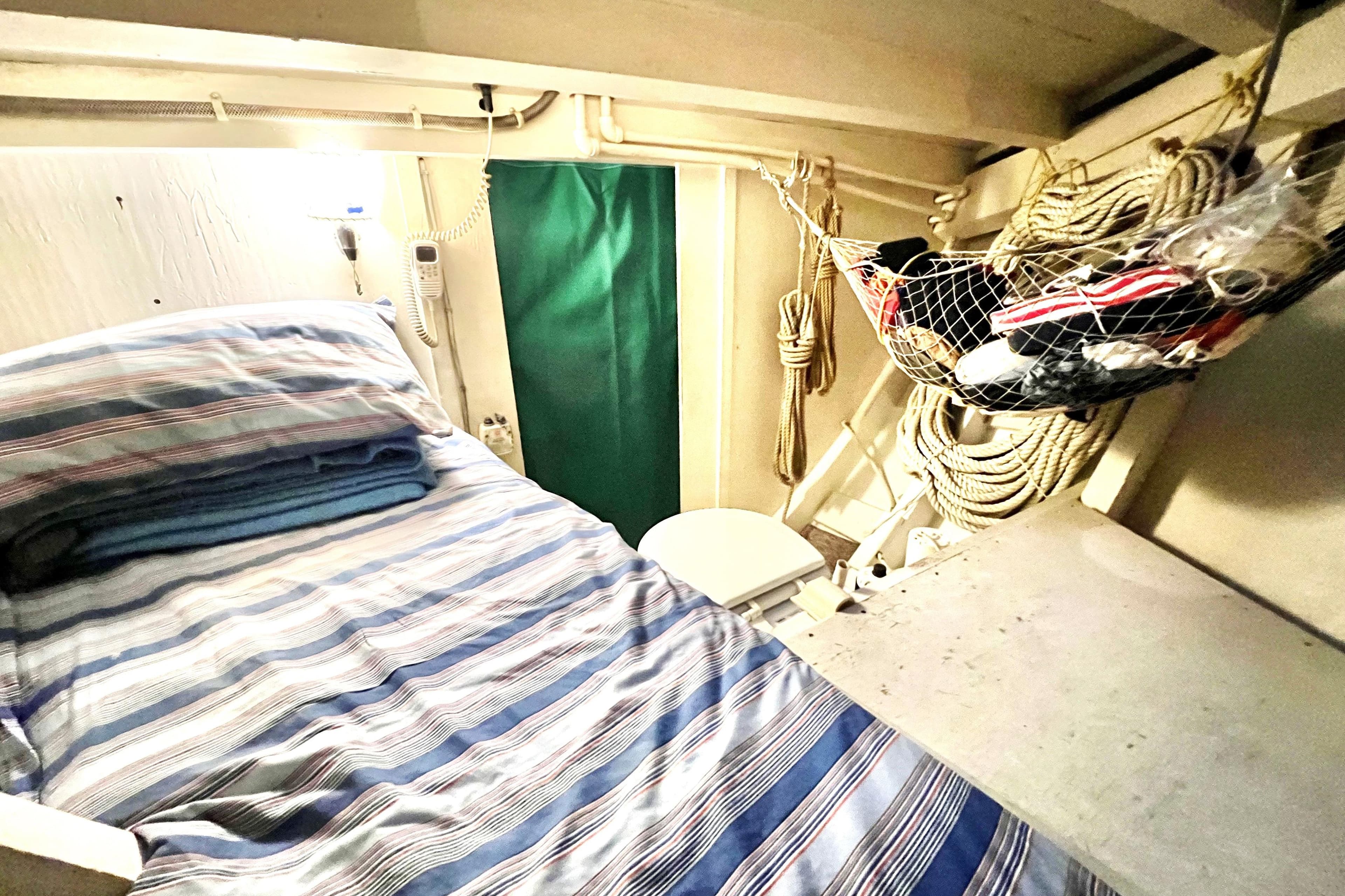 Cozy cabin interior of a 1972 Mills Boat Works Tug Boat with striped bedding.