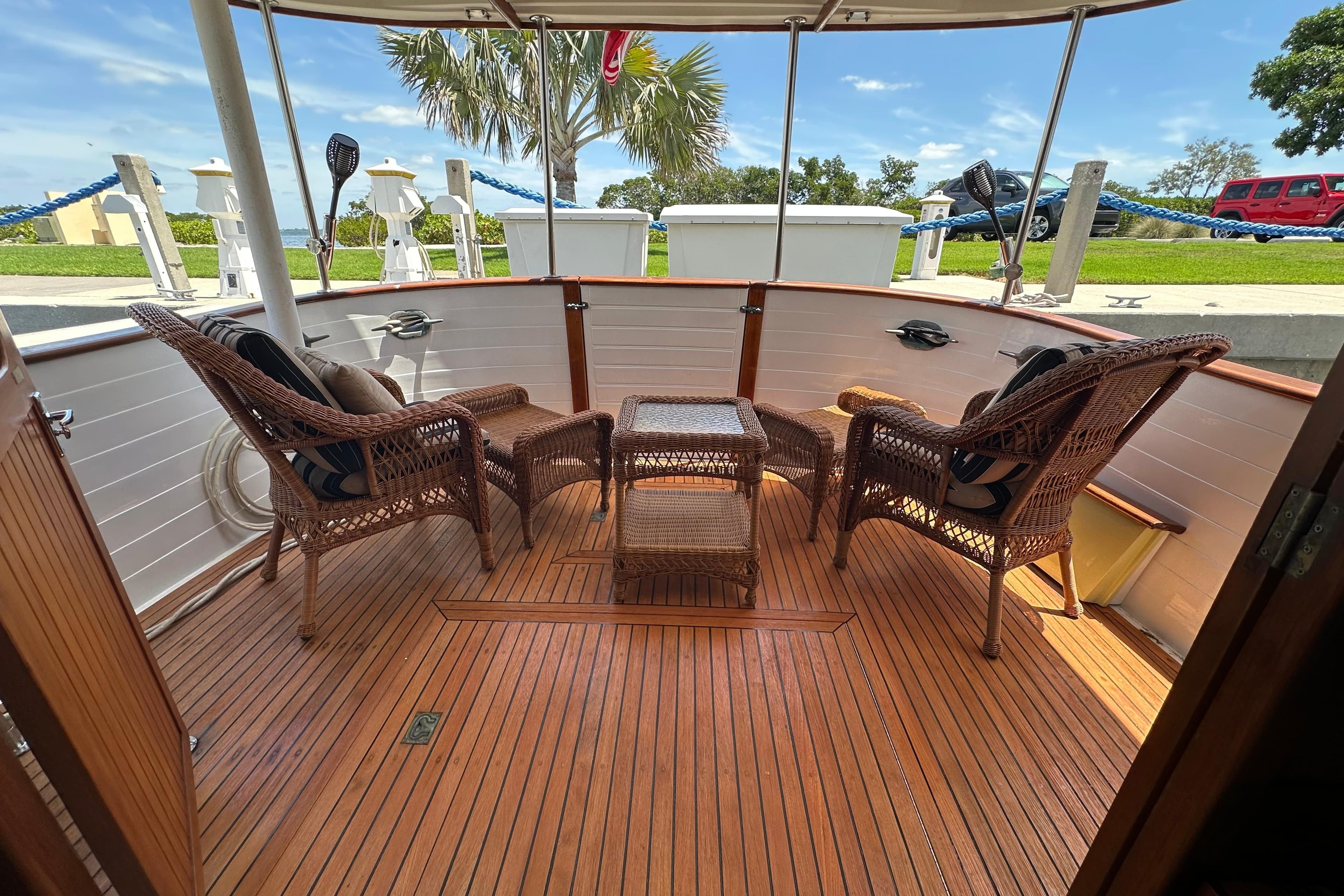 1987 Kadey-Krogen Manatee 36 yacht deck with wicker chairs and table, docked outdoors.