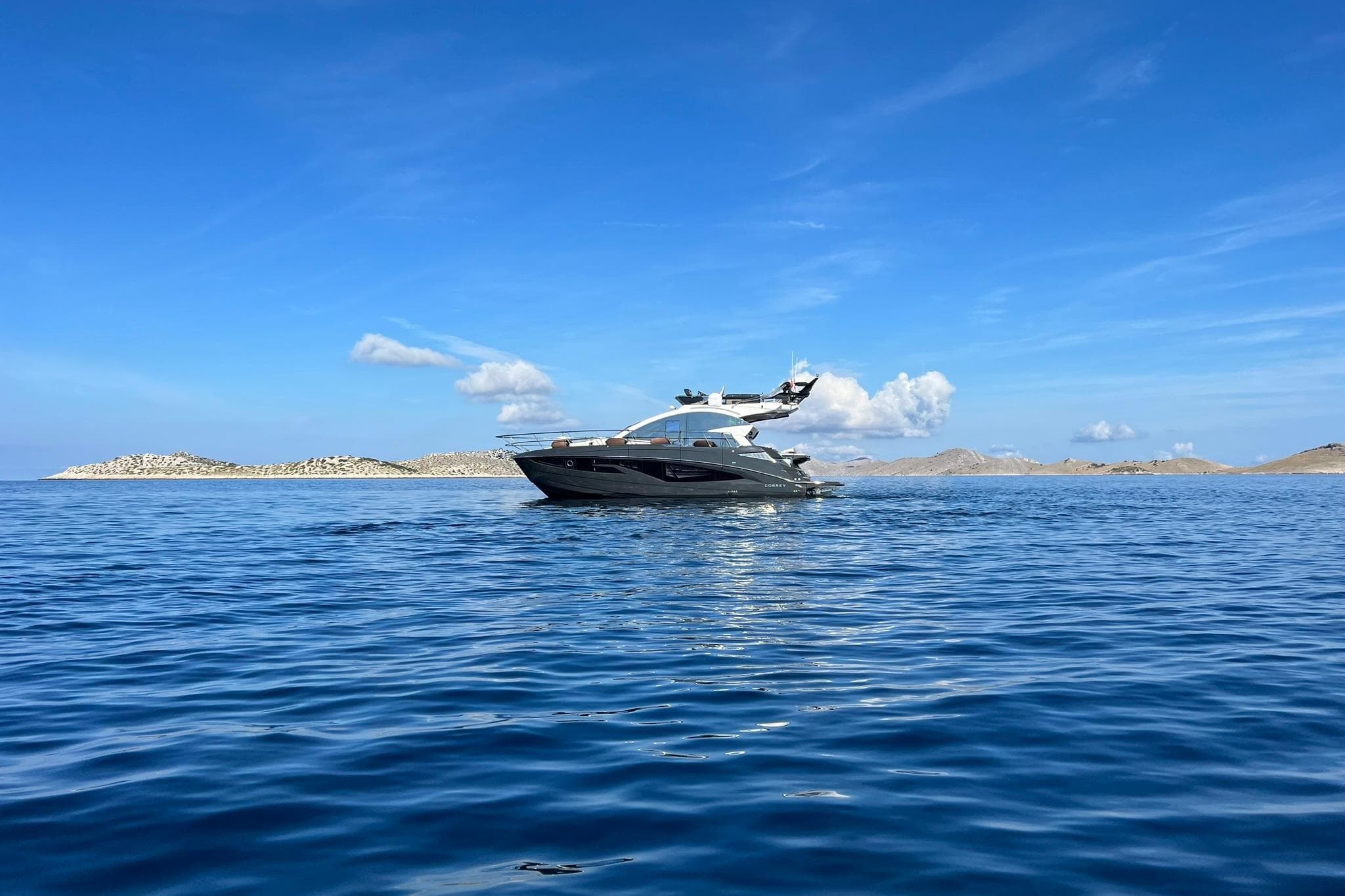 2026 Cobrey 45 FLY yacht cruising on serene blue waters under a clear sky.