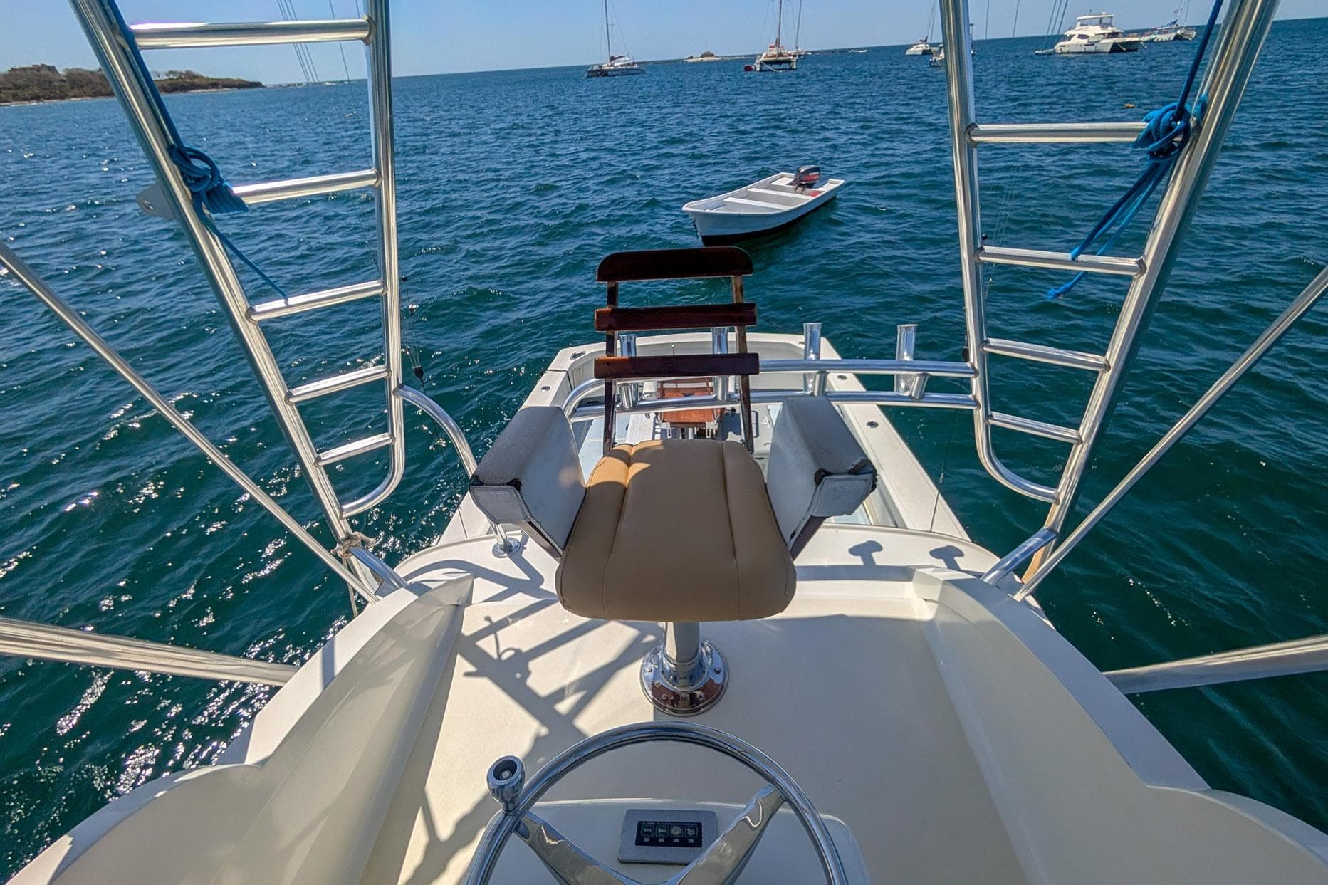 1973 Bertram 31 Sportfisher helm view with ocean backdrop and nearby boats.