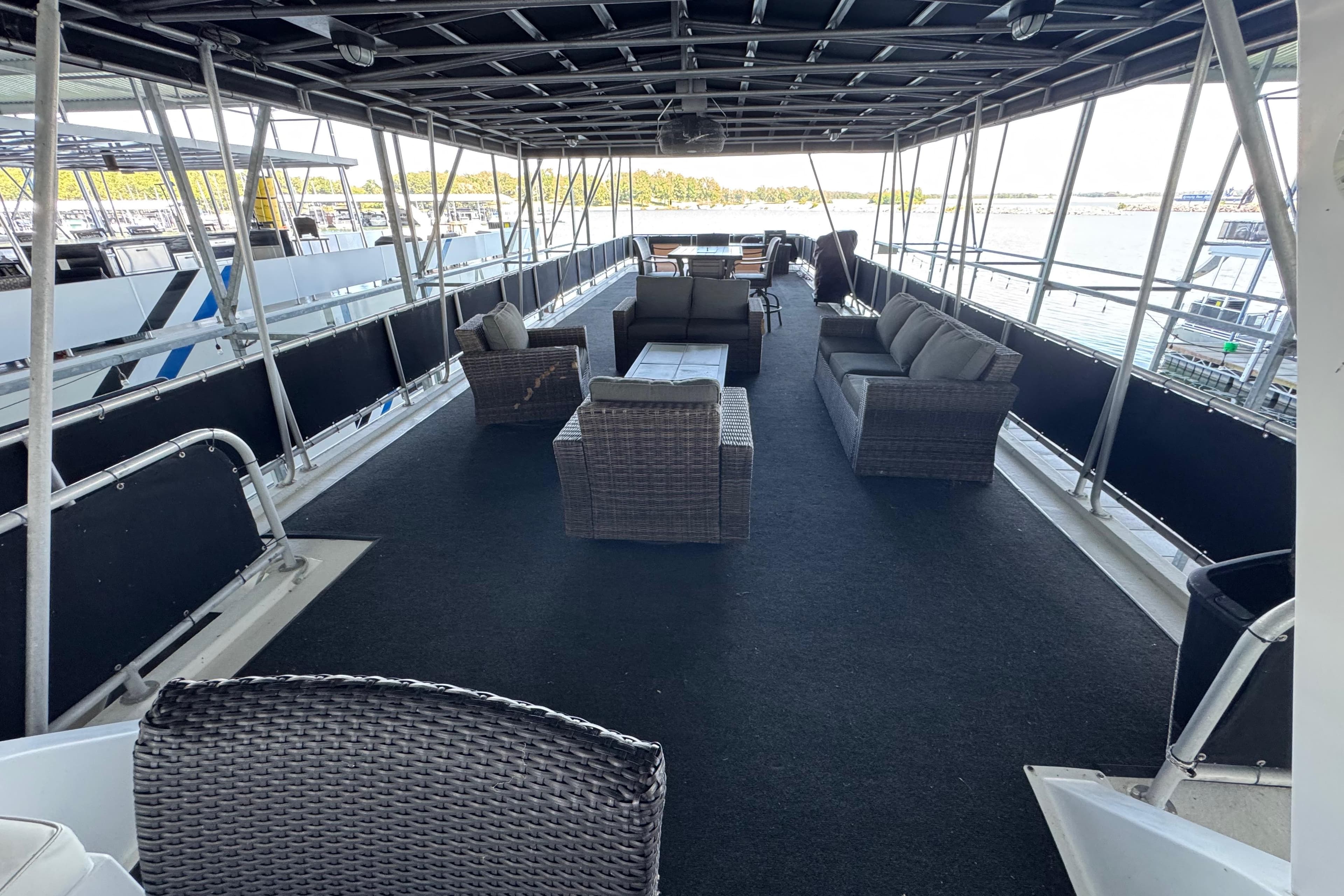Spacious deck of 2004 Starlite 65x16 houseboat with wicker furniture and scenic views.